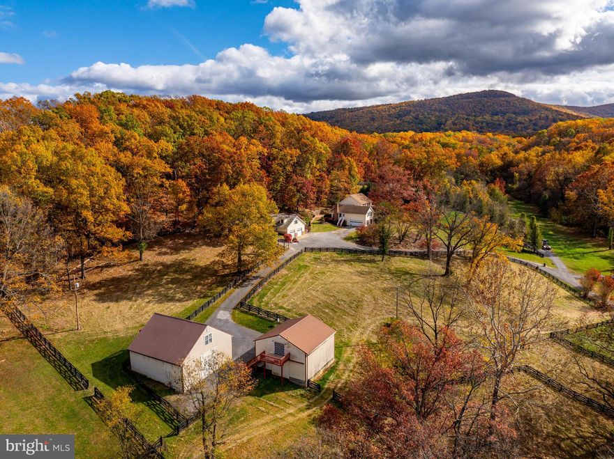 Distinctive family homestead on nearly 11 acres priced to sell UNDER TAX ASSESSMENT value! So many possibilities - Farmette, Family Compound, Horses, Hobbies and more.  An estate that is truly one-of-a kind with so many amenities including:  in-ground pool, barns, stable,  garages, wooded acreage, the list goes on.  NO HOA, no covenants or restrictions - only 3 miles from town! Incredible location with lots of space to enjoy your own private farmstead but with all the convenience of downtown Front Royal and short drive back to DC for commuters.  Close to the Shenandoah River, Skyline Drive, and North Entrance to Shenandoah National Park.  The main house is a colonial style home that has been recently renovated with all new flooring, kitchen and bathrooms. 4 total bedrooms (3 traditional bedrooms upstairs + loft with bathroom above garage).  Master En  Suite has private balcony that overlooks the pool and patio and also features double closets and spacious bathroom with soaking tub and separate shower.  The northern portion of the property is forested,  with lots of woods, perfect for trails and leg room for the kids to explore.  Huge loft (4th bedroom) over the attached garage has its own bathroom, and private staircase to separate entrance.  Main level has a formal living room, separate dining room, large kitchen with new cabinets, appliances and countertops, which opens to a great room that features a wood-burning fireplace.  Huge sunroom/bonus room with lots of light, custom tile, and incredible windows. Awesome patio for entertaining and hosting large dinners, in addition to incredible pool area.  Walkways and hardscaping, and patio walls with true masonry stone and brick.  Many custom and attractive extras at every corner - built-in seating, mature landscaping and much more.  Large covered front porch and enclosed veranda (for the Hot Tub) at the front of the home provides another route to the pool, so the entire home is accessible and functional.  In-ground pool recently refurbished, along with pool-house and impressive custom stone work all around, including retaining walls.  Pool area is connected with lower-level of home, which is a fully finished basement and extra "pool room" for all the towels and floats, then enters into fully finished Rec Room with built-in bar and separate bonus room "den" with wood stove and additional full bathroom.  Additional structures include (1) oversized Detached Garage/workshop with loft above; (2) Barn with several garage bays, separate storage room + loft above with kitchen and bathroom; (3) Stable with 5 stalls and tack room + loft above with kitchen and bathroom.  The barn and stable are situated privately from the main house, with a paved driveway and fenced fields and paddocks.   Extra buildable lot with existing septic, well and driveway is available.  This is an exceptional opportunity for that family compound you've been thinking about.  So many different scenarios that would work for the growing family of people and animals - bring 'em all!  This estate has so much to offer, it cannot be captured in a short listing description...see property brochure for more information in documents section.
