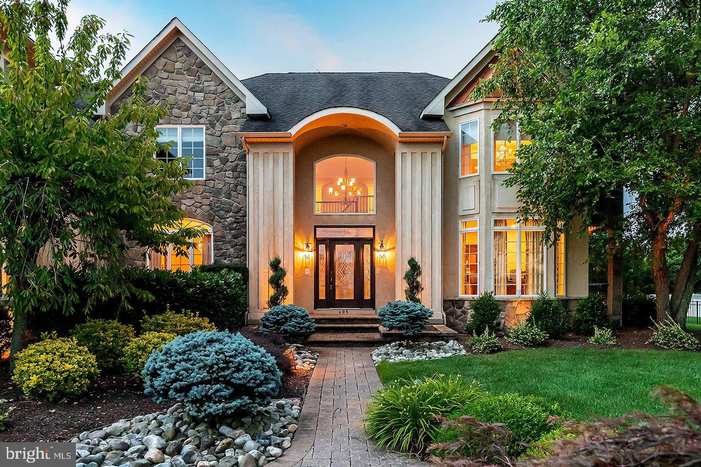This palatial Mullica Hill home is an absolute SHOWSTOPPER! Offering over 7500 sq ft of living space, this estate style home is nestled at the end of a cul-de-sac in the highly rated Clearview school district, and feels like it is straight out of a magazine! This luxury property showcases the ultimate in detail, quality and design, starting with its exceptional curb appeal featuring extensive professional landscaping, paver walkways and landscape lighting. Be wowed in the grand foyer with its soaring 18 foot ceilings and sweeping curved staircase. A home office with upgraded wood trim package and custom window treatments is tucked away behind French doors off to one side. On the left you’ll find the dining room, just waiting for it’s new owners to begin filling it with new traditions over shared meals. The chef’s kitchen is the heart of this amazing home. Here you will find a huge granite island with seating, beautiful fixtures and ample lighting for a well lit work space. The stainless appliance package includes 6 burner cooktop, dual ovens, microwave, dishwasher and ice maker. The butler’s pantry is the perfect space for a coffee bar, with prep sink and separate beverage cooler. The kitchen opens to the bright and sunny family room, with stone front gas fireplace, and triple full view French doors looking out to the stunning backyard. The formal living room has dramatic ceiling to floor windows, gas fireplace, and catwalk overlook from the second floor hallway. The western wing of the home offers living space including sitting room and sun-drenched solarium, den with private sitting porch and bath. Upstairs you will find TWO owner’s suites! The primary owner’s suite is a perfect place to retreat, with a sitting area and cozy gas fireplace, recessed lighting, tray ceiling and dual closets. The en suite gives the feel of a high end spa with eye-catching pebble stone shower with seamless glass enclosure, dual sinks with pendant lighting and vanity seating area, with separate water closet. Down the hall there is a junior suite with bathroom and large walk-in closet; another large bedroom with Jack and Jill bath connecting to yet another bedroom. The second owner’s suite is at the far end of the hall with private bath and two big closets! Head down to the lower level and appreciate the epitome of craftsmanship and attention to detail in the custom finished basement. Notice the dramatic brick wall and rustic lighting in the stairway! The granite bar with stacked stone facade and accent lighting is perfection. You can fulfill your entertaining dreams here, where you have ample seating, dishwasher, wine fridge, beverage fridge, sink, ice maker. The living room area has a stacked stone fireplace and half bath. No need for that gym membership anymore, since the home gym is perfectly designed for all your workout needs. Once you step foot into the backyard you are never going to want to leave, as this outdoor dream is better than any island resort! Extensive paver walkways and a patio area lead you to the gunite saltwater pool with hot tub, Baja sun step and two waterfalls. But the pièce de résistance is the outdoor pavilion! With it’s warm toned wood ceiling, stacked stone fireplace and large bar; to the built in Weber grill, two burner cooktop, refrigerators, icemaker and prep sink, you’ll have everything you need for outdoor entertaining right at your fingertips. The backyard also has a built in fire pit, and a play area, yet still offers so much additional open space. Easy access to Philly and shore areas , historic Mullica Hill and only 2 miles to the new Inspira Hospital.