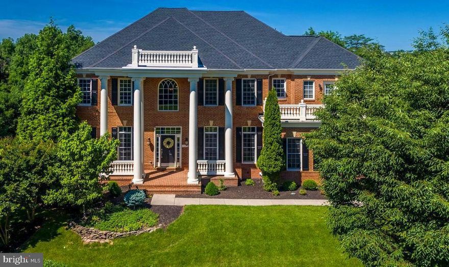 Stunning Wentworth-3 model by Basheer & Edgemoor. This stately home with magnificent columns has all you need to live the good life! A bright kitchen with a gorgeous, giant Caesarstone island & countertops, looks out on the woods behind and opens up to the light filled, 2-story family room with overlook. You are welcomed in to elegance on Brazilian Cherry hardwood flooring on the main with a large office, formal living room and an abundance of windows. There is plenty of space to entertain in this 8050 sq ft gem with a large deck which is partially screened overlooking the brick patio and woods, a fantastic theater room with plush seating & wet bar in the basement where your friends and family can gather for a game of pool. The theatre in basement with plush seating and full rack of Yamaha & Boston video and sound equipment is steps away from the wet bar and pool table where many more memories will be made!  When all done, you can retire to one of the balconies or the huge master bedroom with added fireplace. A $10,000 credit is being offered for you to pick out the carpet of your choosing to meet with your tastes & lifestyle! The irrigation system makes keeping the yard beautiful easy! (Theatre seating, full rack of Yamaha & Boston video and sound equipment, pool table and TV in family room, basement and master bath convey. There are other optional items such as china cabinet and foyer console that may convey as well.)