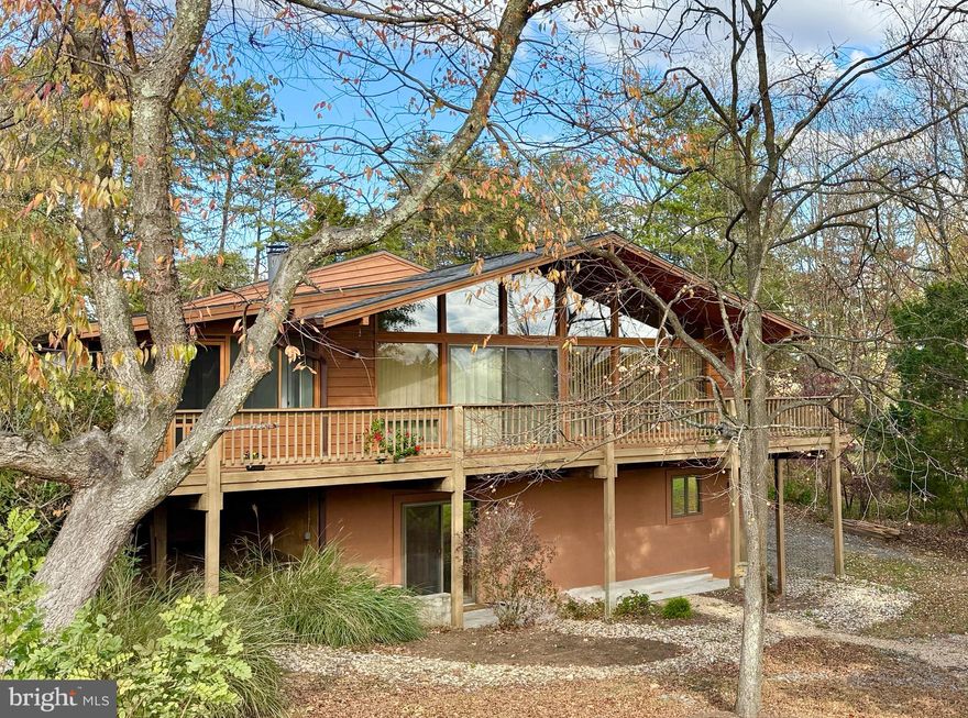 This refined three bed/three bath mid-century home has an unmistakable sense of style and architectural presence—clean lines, warm materials, and a seamless indoor–outdoor flow. Elevated among the treetops and overlooking the second hole of the Mountain View Golf Course in The Woods, this cedar-clad home blends modern updates with timeless design creating a space that lives beautifully as a full-time residence, a multi-generational home, or a luxe short term rental. 417 Tecumseh Trail delivers the essence of mid-century living and a lifestyle defined by serenity, recreation, and effortless retreat. Recently inspected (annotated report attached to listing) and freshly revitalized with newly-stained cedar lap siding; a new roof with transferable warranty (attached to listing); and a new 50-gallon water heater and expansion tank—this property offers peace of mind at a stellar price. The HVAC just had it's regular annual service. It was cleaned and serviced (and while slightly vintage)—has a clean bill of health! The completely updated kitchen (granite countertops; stainless LG appliances;  solid wood-faced, soft-close cabinetry; Delta faucet) anchors the main living level, framed by vaulted ceilings and that expansive glass wall that draws in all the natural light that forms the glow around this house. The main living area is centered around a wood-burning, white-washed brick fireplace and that midcentury wall of windows creating a rich focal point. The large, screened-in porch feels super open due to the two skylights and is accessible from both the living room and the primary suite. Below the porch and the huge deck, a fire pit offers four-season outdoor experience.  The home's thoughtful layout includes a standout feature: a lower level walk-out suite—perfect for guests, extended family, or income opportunities. The home has so much storage and so many closets—a coat closet, a linen closet, a walk-in pantry, a walk-in closet/dressing room and a fully-encapsulated crawl space! The lot has ample space should the next owner want to add a garage or carport.  (HOA Docs including bylaws attached to this listing) This home does not currently have a membership to the Woods Club. Golf is open to the public. OPEN HOUSE PARTIES THIS WEEKEND: Saturday and Sunday 11/22-11/23 1-4pm. Gorgeous House +  Food + Drink + Neighbors + Friends.  All are invited + nosey neighbors encouraged :) Staging and Interior Design by Honey House.
