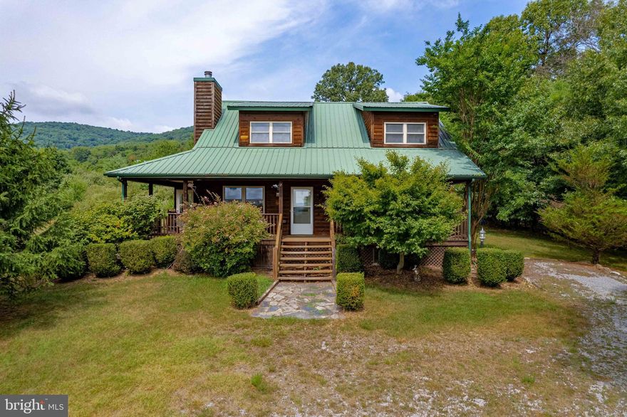 Welcome to your tranquil retreat at 243 Cressida Dr! This log home, nestled on a sprawling 6-acre lot in picturesque landscape of Hedgesville, WV offers a unique blend of rustic charm and modern comfort. Featuring 3 bedrooms, 2 full bathrooms and oversized loft. Boasting 2080 square feet of living space, the open floor plan includes a cozy great room with a floor-to-ceiling stone fireplace. 
The primary suite provides a peaceful escape with its own private deck while additional bedrooms offer ample space for guests or family. Great room opens to large kitchen with island, back yard view, ample cabinetry and counter space.  Enjoy your morning coffee or evening sunsets on the expansive wrap-around deck with wooded surroundings on your 6-acre lot. This property is perfect for those seeking both relaxation and  privacy. Whether you're seeking a full-time residence or a serene getaway, this property is a must-see.