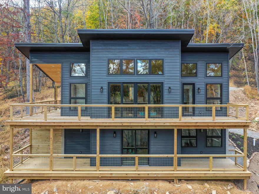 ** Offer Deadline/Highest and best by Monday 11/17 at 5pm for consideration.  **  Welcome to 933 Timberline Drive, where modern elegance meets rustic charm. This contemporary cabin is sleek yet understated, stunning yet unpretentious.  Designed with style and simplicity this 2-bedroom 2-and-half-bath home checks all the boxes!  Step inside to the breathtaking great room, framed by expansive windows that flood the space with natural light and showcase panoramic views of the ancient Appalachian Mountains. Upscale flooring, tongue-and-groove cathedral ceilings, and wide-open layouts create an airy, inviting atmosphere.  The gourmet kitchen boasts stainless steel appliances, modern fixtures, soft-close cabinetry, and a 8-foot quartz island doubling as your dining hub!  Eight-foot-tall wall-to-wall double sliding glass doors open seamlessly to the wraparound deck, ensuring perfect indoor-outdoor flow. Cable railings throughout the home and exterior preserve unobstructed sightlines to the surrounding beauty. Retreat to the primary suite, complete with a luxurious full bath and an oversized glass door leading directly to the deck for uninterrupted mountain views you will never get tired of!  Both bathrooms feature floor-to-ceiling ceramic marble tiled showers, live-edge Chestnut wood slab vanity tops, and elegant vessel sinks.  The sleek, modern basement offers polished space that is both practical , functional and on-trend.  A spacious recreation room, second bedroom with closet, full luxurious bath, ample storage area, and a separate mechanical room.  This newly constructed home has central air and heat, metal roof and LP smartside lap siding providing reliable, long-lasting materials and low maintenance.  The Timberline cabin sits on 2.22 wooded acres, providing privacy, quiet surroundings and room to relax with a book, gather around a campfire, or observe the abundant wildlife. For the adventurer and outdoor enthusiast Trout Pond State Park is just minutes away for hiking, fishing, boating, and swimming.  The great George Washington National Forest is steps away, delivering thousands of acres for hunting or just roaming free and enjoy the wide open space!  Less than 100 miles from Dulles Airport and the Northern Virginia suburbs – your mountain get away is calling!