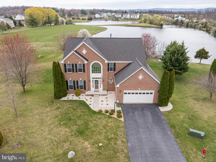 Look at that view! Offering one of the best pond views in the neighborhood, this is the home you have been waiting for in Locust Hill. You will want to spend your mornings watching the breathtaking sunrise over the pond right from the comfort of your deck or morning room! This meticulously maintained brick-front colonial adjoins the pond and golf course and sits on a cul-de-sac offering 4 bedrooms and 2.5 bathrooms. Inside, you will find an open floor plan with a formal living room and formal dining room with bay windows. You’ll love the large living room that features a gas fireplace and hardwood flooring that is open to the kitchen with 42” cabinets, an island, and unique cherry red Big Chill appliances. The kitchen also boasts hardwood flooring, gas cooking, and a pantry. There is a morning room with a vaulted ceiling just off the kitchen with stunning views of the pond and access to the large rear composite deck with stairs leading to the outdoor patio and portable hot tub under the deck.  There is also a half bathroom on the main level as well as a laundry room and access to the garage. Upstairs, you’ll find a large primary bedroom with a vaulted ceiling, a large walk-in closet, and a primary bathroom with soaking tub. There are three other bedrooms upstairs that share a hall bathroom. The large unfinished basement with rough-in bath is ready for you to finish into additional living space and has a walkout to the rear yard, patio, and the secure storage area under the deck. This home has had many updates over the last 6 years including a new roof, 2 HVAC units, tankless water heater, and a new water softener. The sellers are also willing to convey a 2021 Cub Cadet riding mower, push mower, all outdoor furniture, outdoor rugs, umbrellas, extra refrigerator, deep freezer, gym equipment, and more at no charge. Convenient location for commuting to VA, MD, or DC!