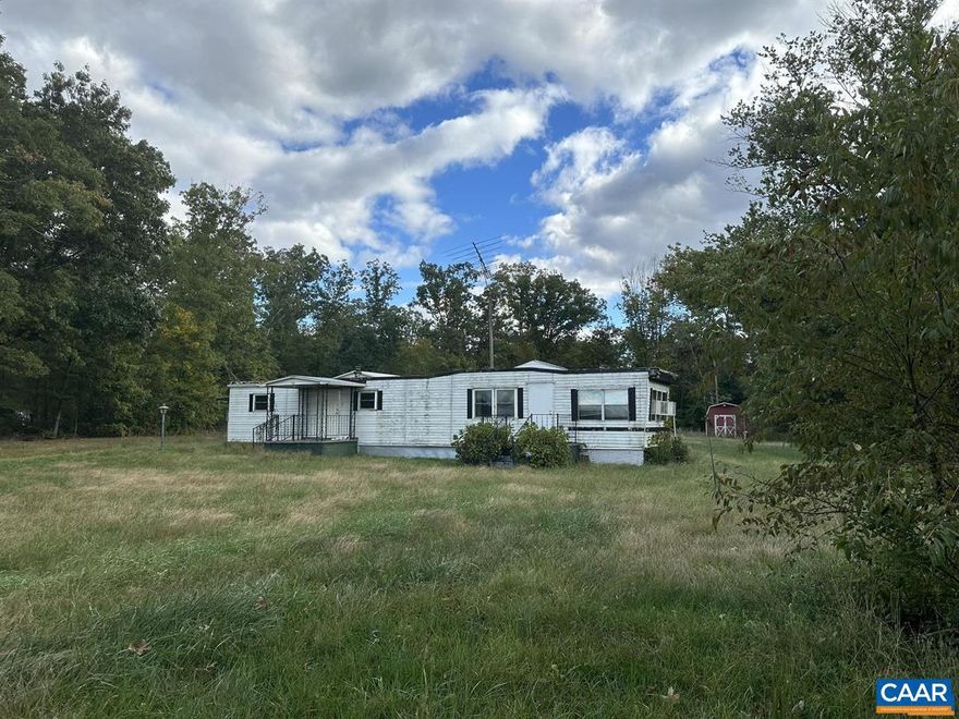 Singlewide mobile home on 1.44 acres. Level lot fronting on Rt. 20 across from Orange Airport. Gravel driveway, , massive carport with power panel, cinderblock outbuilding/workshop and wood shed. Trailer is old and will need some work to be made livable. Want a good, level lot with county water and easy access to town? Remove the trailer and build new! Also listed under LAND (MLS #657930).