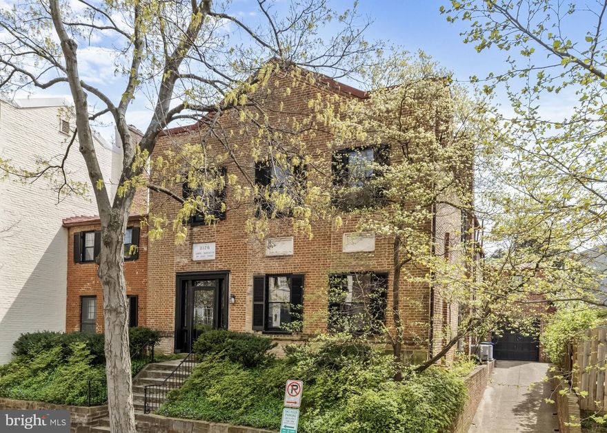 Perfectly located in the East Village this historic brick Georgetown house is both stately and livable. Above the front door is a marble block with the inscription “Amor Signatur in Hac Domo” and the large original corner stone engraved with “The Lancaster School 1811” remains. The front door has both fanlights and sidelights and is an indication of the Federal authenticity that will follow inside. The entry hall is 13’ wide with original wide-plank flooring and flows all the way through to the large south garden. The rest of the ground floor layout is both classic Federal and high functioning. On the right of the hall are two large rooms with fireplaces and 12’ ceilings and to the left of the hall is a cozy library with a fireplace and a door to an arbored section of the garden. This part of the house dates to 1790 and contains an original mural by Olin Dows. The center hall also has a coat closet and new powder room. The spacious dining room and large eat-in kitchen are connected by a full butler’s pantry. The pantry has a back stairway to the second floor, and doors to both the garden and the driveway. The modern granite kitchen contains a bay window which fits a table for four and feels surrounded by the garden. Every part of the ground floor is special - from its 19th century details like the flooring, moldings, chair rails, mantels, windows sills, and more - to its abundance of windows capturing light from every angle.
 
The main staircase is flooded with sunlight from a south-facing Palladian window and leads to the commodious landing with access to three ample bedrooms and new marble bath. Each of these bedrooms has very high ceilings and a fireplace. There are also stairs to a fourth bedroom accessed by a hall with a south-facing window and a large linen closet. The primary bedroom has an updated marble bath en suite. This floor maintains the exquisite original details and lofty light-filled rooms of the entry level. This is rare in Georgetown where often the second floor loses some of the grace of the public rooms.
 
The rear of the second floor is accessed by a back staircase off the butler’s pantry. This section of the house has two bedrooms and one bath. These bedrooms have nice light from two exposures each. There is also a large storeroom with windows on two exposures. The very dry basement has two unfinished rooms.
 
The south garden is large and tranquil. There is a lawn with brick pathways and brick walls with mature perennial plantings including three espaliered fig trees. The shady arbor off the library is secluded and there is a 30’ by 10’ pool flanked by a studio with large glass doors. This building has another full bath and connects to the garage.