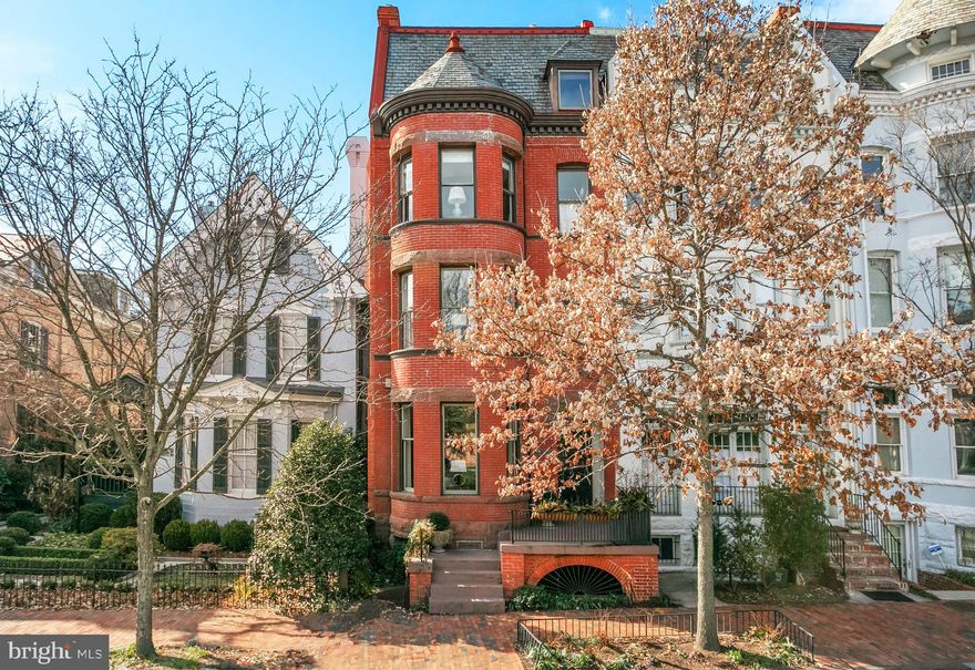 This impressive 6 bedroom,  5 and 1/2 bath semi-detached brick row house is ideally situated on a prominent street in Georgetown’s historic East Village. The Victorian-style home circa 1894, showcases stunning architectural details, including exterior dentil trim, arched brickwork, and an elegant front turret. Its highly desirable layout features a seamless flow between spacious rooms, bathed in natural light from large windows and elevated by high ceilings throughout. The graceful front vestibule opens to a welcoming entry foyer with  limestone floors. The living room, which can be closed off with pocket doors, boasts intricate moldings, a beautiful bay window, and a fireplace framed by a detailed marble mantle. The adjacent dining room includes another fireplace with marble accents and the original restored Italianate crystal chandelier. At the rear of the home, the fabulous gourmet eat-in kitchen is equipped with top-tier new stainless steel appliances, a generous center island with storage, a fireplace, and a built-in desk. Two exterior doors lead to the rear terrace and garden. The second level is home to two bedroom suites, including the luxurious primary suite. The primary bedroom features a charming bay window, a walk-in closet, a fireplace, and a private office/sitting room. The elegant primary bathroom is fitted with dual vanities and a frameless glass shower. The second bedroom on this floor also has an en-suite bathroom and overlooks the rear garden. On the third floor, two additional bedrooms offer fireplaces, large closets, and share a well-appointed hall bathroom with a linen closet. The top floor offers versatile open space with plentiful storage, exceptional views and could function as a fifth bedroom. It includes an en-suite marble bathroom with a frameless glass shower. The lower level features a separate entrance and provides a spacious recreation room, ample storage, and a convenient in-law or staff suite with separate access, a kitchenette, and a full bathroom. The laundry room, located on this floor, is equipped with a utility sink, folding station, cabinetry, and a second refrigerator and freezer. Off-street parking ( with electric car charger ) for one car is available in the rear. This remarkable residence is just steps to Dumbarton Oaks Park, and a short walk to the Evermay estate and as well as distinguished shopping and cafes.