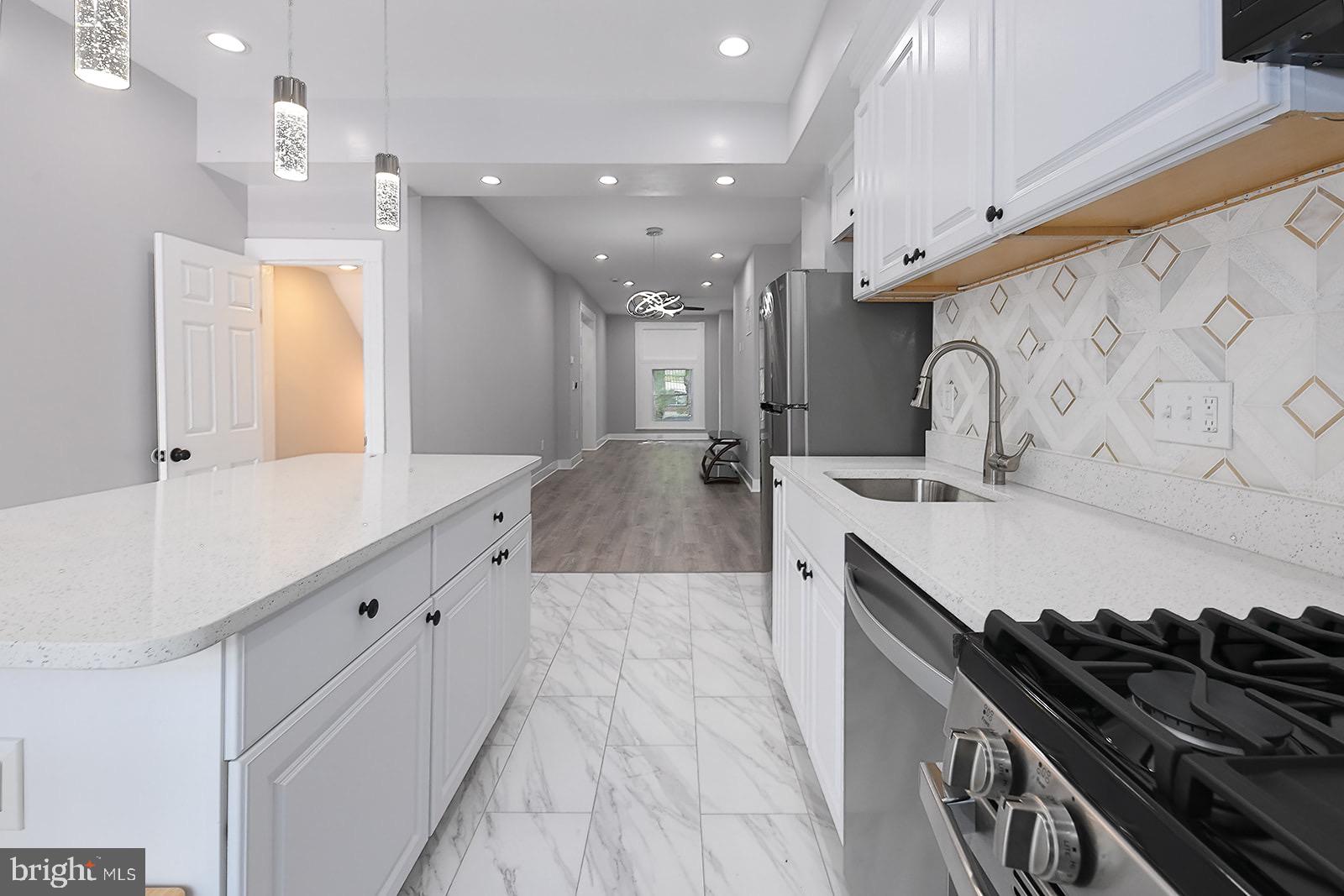 Beautifully renovated Federal-style Baltimore rowhome offering a true move-in ready experience in the McElderry Park neighborhood, just minutes from Johns Hopkins Bayview. Step inside to an open concept main level featuring a large kitchen island with knee bar seating, granite countertops, stainless steel appliances, above-range microwave, motion-activated faucet, and stylish tile floors. Luxury vinyl plank flooring flows throughout, complemented by modern finishes, ceiling fans in the bedrooms, and abundant natural light. The second level includes two bedrooms, a full bath with walk-in tiled shower, and a flexible middle room with closet that works perfectly as an office or bonus space. The fully finished basement adds even more living options with a bedroom, full bath, common area, and washer/dryer. Outside, enjoy a private rear patio, while the new roof and brand-new AC system provide peace of mind. Surrounded by neighborhood revitalization and convenient to parks, schools, and commuter routes, this home is an excellent choice for buyers and agents seeking style, function, and value within the city.Don’t miss your chance to own a fully renovated city home with modern finishes and timeless character—schedule your showing today and experience everything this property has to offer!