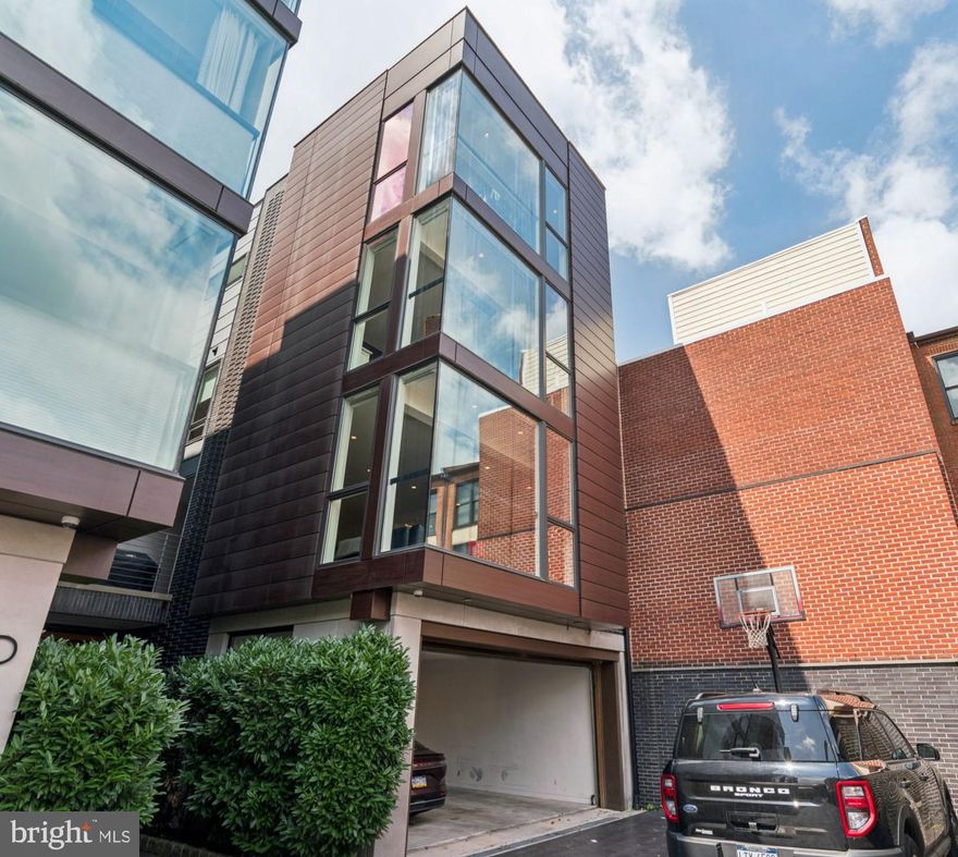 Welcome to 206 N 22nd Street, Unit E—a spectacular 4,200 square foot modern townhome tucked away in the heart of bustling Logan Square. Combining luxury, smart technology, and thoughtful design, this 4-bedroom, 4 full and 2 half-bath home offers unmatched space and privacy in one of Philadelphia’s most convenient neighborhoods. Nestled privately at the end of the driveway, Unit E features 4-car parking (2-car garage + 2-car driveway), an elevator to all levels, and 4 private outdoor spaces—including a wraparound rooftop deck with panoramic skyline views. Enter through your private garage entrance or your lush pathway into an elegant foyer with a flexible use en-suite.  The modern oak floating stairs bring you to the main level, complete with a chef's kitchen including a 42" Sub-Zero refrigerator, 146 bottle Sub-Zero wine fridge, 36” Wolf cooktop & hood, 30” Wolf wall oven, microwave, and white Quartz countertops.  Floor-to-ceiling windows on the northern exposure ensure streaming sunlight throughout the day.  Gas fireplace and outdoor area perfect for grilling. The third floor features two large en-suite bedrooms, each with walk-in closets, a guest room or den, and a spacious laundry room with full-size washer and dryer.  The fourth floor features the primary suite, complete with walk-in closet, office, and a stunning bath with a jacuzzi soaking tub, 6-jet rain shower, and heated tile floors.  The next level is a smaller kitchen and powder room, accessing a wrap-around roof deck with views in every direction. Other home details include Full Control4 Smart Home system (music, lighting, security, Nest thermostats, 5-zone HVAC, Motorized custom blinds and built-in speakers throughout, Floor-to-ceiling windows for the most amazing natural light, and one year left on the tax abatement. Walking distance to Whole Foods, Art Museum, Giant, The Barnes, Franklin Institute and so much more.  Easy access to Penn, Kelly Drive, The Parkway, and 76.