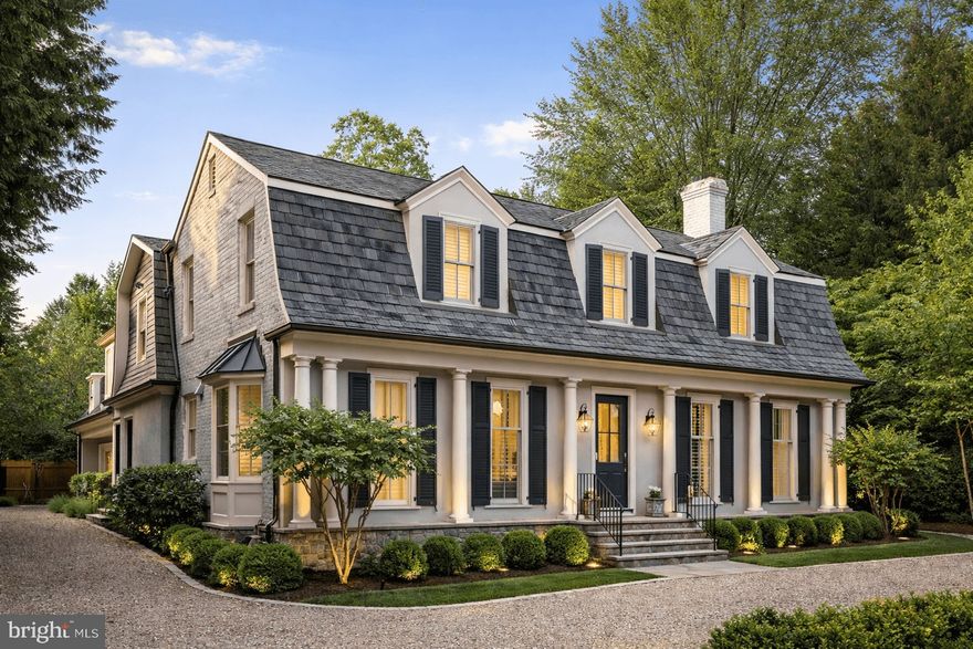 Set in one of the most prestigious enclaves of historic Langley Farms, this timeless residence blends classic East Coast elegance with modern luxury and thoughtful design. Fully redesigned by Foster Zimmerman Architecture and renovated by renowned Galileo Construction, the home reflects exceptional craftsmanship, architectural integrity, and sophisticated livability throughout its approximately 6,200 square feet.

The stately façade is defined by beautifully proportioned French Colonial architecture, highlighted by a distinctive mansard-style roofline, symmetrical dormer windows, and traditional shutters that create an immediate sense of refinement and balance. The front of the home was redesigned with substantial round columns and stone accents while the circular driveway and manicured landscaping enhance the estate-like setting. Mature trees provide both privacy and a serene, park-like environment.

Inside, the home is fully updated and meticulously maintained, featuring elegant dark wood floors throughout and a layout designed for both formal entertaining and comfortable everyday living. The large formal living room is anchored by a remote-controlled gas fireplace, while the elegant first-floor office showcases custom cabinetry and refined detailing. Designer light fixtures, custom plantation shutters, and built-in cabinetry throughout further elevate the home’s polished aesthetic.

At the heart of the residence, the all-white chef’s kitchen offers both beauty and function, featuring inset cabinetry, an oversized marble island, paneled Sub-Zero refrigerator, Wolf range and cooktop, paneled Bosch dishwasher, built-in under-counter microwave, and approximately nine feet of glass display cabinetry. A walk-in pantry provides additional storage and convenience, making the space ideal for both daily living and entertaining.

The home includes four bedrooms and five-and-a-half baths, with a thoughtfully designed guest suite that functions as a private retreat. The suite features an oversized living room with custom built-ins, a spacious bedroom, and a marble bath, offering exceptional flexibility for guests or extended stays. An elevator services all three floors, ensuring ease of access throughout the home.

Modern comfort and convenience are seamlessly integrated, with the entire house wired for sound and media and supported by a commercial-grade Kohler whole-house generator. Additional features include a walk-in linen and coat closet, multiple custom built-ins, and an oversized three-car garage.

Outdoor living is equally impressive. The expansive two-tiered flagstone patio is designed for year-round enjoyment and includes a built-in gas firepit, built-in gas grill, and a new sunken Caldera spa surrounded by stone and Ipe decking. Professional landscaping, elegant water features, and thoughtfully designed exterior lighting set on timers and sensors to provide both ambiance and security.

The home has been renovated and expanded significantly over the years as reflected in its current stucco and stone siding, architectural shingle roof, all new windows and exterior doors, a covered side porch, a garage addition with guest suite above, a back stairway, and an expanded lower level, which offers versatile space including a workout area, butler kitchen, full bath, and large finished storage.

Combining timeless architecture, modern systems, and exceptional outdoor living, this Langley Farms residence presents a rare opportunity to own a fully redesigned and meticulously maintained home in one of McLean’s most prestigious and historic neighborhoods.