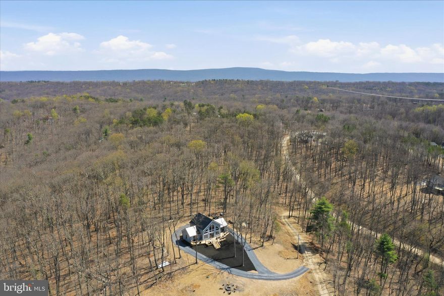 Some homes have a view… and then there are homes like 432 Lost Point Lane where EVERY room feels like a front-row seat to West Virginia beauty. Imagine waking up to breathtaking scenery, sipping your morning coffee while soaking in mountain views, and ending your evenings watching the sunset from the comfort of home. This is more than a house — it’s the lifestyle people dream about. From nearly every window, nature steals the show and creates the peaceful retreat you’ve been searching for. Whether you’re looking for a full-time home, mountain escape, or investment opportunity, this one is truly unforgettable. Trust me… the photos are stunning but seeing it in person is a whole different experience. 
Imagine waking up every morning to the views this home provides! Set on over 2 acres, 432 Lost Point Lane in Berkeley Springs, West Virginia offers a setting that feels private and connected to the landscape, with panoramic vistas that are rarely found. Wanting a true West Virginia Mountain getaway that is newly constructed with upgrades to match? Keep reading!  Built in 2025, this custom home blends craftsmanship with thoughtful design across approximately 1,900 square feet. Wood flooring runs throughout, complemented by custom tiled showers and a well-appointed kitchen featuring high-end appliances, including an adjustable waterfall faucet at the sink with all the bells and whistles. Built with top-tier insulation, the home supports comfort and efficiency in every season. A standout feature is its ADA-compatible design—an uncommon find in today’s market—featuring wider doorways, lever-style handles, tilted mirrors, and a roll-in tiled shower, all seamlessly integrated into the home’s layout. Two main-level primary suites each include full baths, offering a balanced and functional design. An additional full bath in the loft bedroom #3 provides added flexibility. There is no part of this home that has not captured the views! When you close the doors to the bedrooms, you are still blessed with amazing views and access to the massive front deck. The home is fully furnished, creating a turnkey opportunity from day one. Just move right in! Enjoy community water access just moments from your doorstep—perfect for fishing, kayaking, and relaxing by the water. Located less than two miles from Cacapon Resort State Park, with easy access just 6 miles to the Virginia line and a short drive to historic Berkeley Springs, this location offers both recreation and convenience.
. Every detail supports a lifestyle centered on ease, comfort, and the surrounding view. Book a showing today! This one is a rare find in this market and is ready for you to call home!