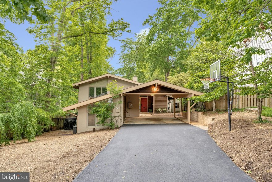 Welcome to 6253 N. Kensington Street, an inviting, light-filled home in McLean’s sought-after Franklin Park. With over 2,800 sq ft of finished interior space and an additional 340 sq ft cedar-paneled screened porch, this property blends mid-century charm with contemporary comfort for a lifestyle built around connected spaces, functionality, and flow.

The main living area features a modern chef’s kitchen with an induction cooktop, two dishwashers, a beverage fridge, a serving bar, and a walk-in catering pantry. The kitchen and open dining area comfortably seat up to 17, while the entire main level, including the screened porch, can host 25+ guests, perfect for seamless entertaining. A natural wood-burning fireplace with a full-length raised hearth anchors the living space, adding warmth and character. Bifolding glass doors open onto the screened porch, creating effortless indoor-outdoor flow for larger gatherings. The expansive main level primary suite includes a large sitting room, a home office area, and a spacious bathroom. The suite also offers ample closet space for storage and organization. A separate den with vaulted ceiling and tons of natural light makes a welcoming home office, study or even a guest room, with easy access to the full bath.

An extension of the home’s living space, the four-season porch has direct access to the back deck and yard. It features vaulted ceilings, skylights, seasonal plastic inserts, dining space for 12, a lounge area for 6, ceiling fans, and cedar-paneled walls that create a cozy, cabin-like atmosphere.

The upper level offers a unique and flexible layout, with vaulted ceilings and large windows that evoke a “treehouse-like” feel. Two bedrooms can be used separately with a sitting room positioned in-between them, or a hallway door can close off the space to offer the privacy of a two-bedroom, one-bath suite. The sitting room comfortably fits a U-shaped desk for work-from-home setups. The third upper-level bedroom and a full hall bath complete the space.

The exterior is both tranquil and low-maintenance with a private backyard surrounded by mature trees, two grilling areas, a fire pit, and seating for 12+ guests. Notable features include wood flooring throughout (marble entry and marble den); dimmable recessed lights and illuminated glass cabinets, clever storage solutions with pull-out, under-stair compartments and hall bath built-ins, outdoor storage: utility closet, garden shed, and bike hooks. The covered carport and fieldstone breezeway provide access with skylights to the front door. Located in the McLean High School pyramid, with public water/sewer, and just minutes from downtown McLean, Arlington, and DC, this home offers the perfect blend of serenity and convenience.