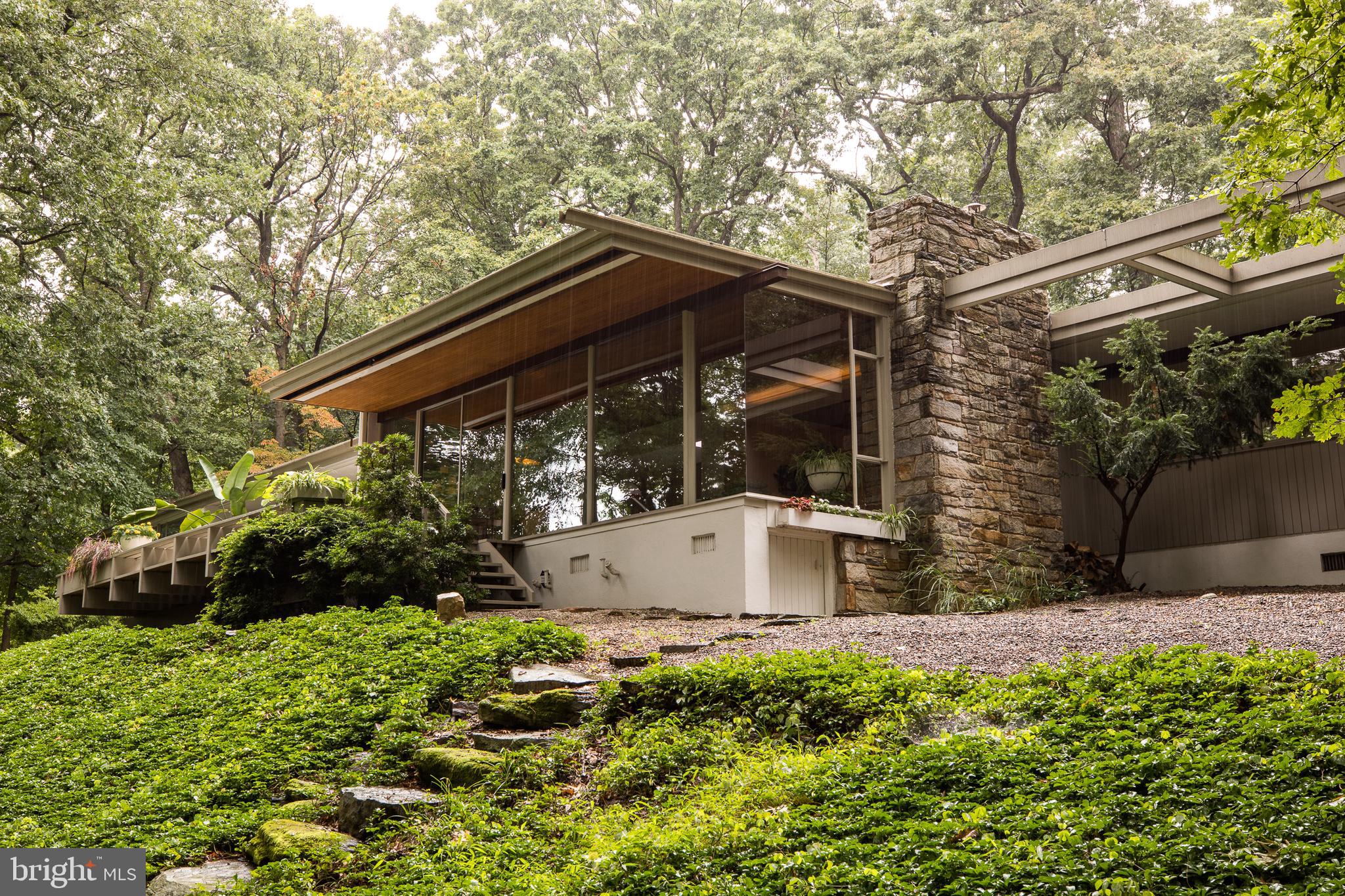 Richard Neutra’s Coveney House: A Timeless Mid-Century Masterpiece
Nestled on a serene two-acre wooded lot in Gulph Mills, the Coveney House stands as a testament to the genius of Richard Neutra, one of the 20th century’s most celebrated modernist architects. Commissioned by David and Sarah Coveney for their growing family, the home was completed in 1963. The striking single-story residence is one of only six private homes Neutra designed in the Philadelphia area. For over half a century, this home has been preserved and thoughtfully updated, offering a legacy of thoughtful design and family devotion that awaits its next stewards.
The dramatic living room anchors the home with its floor-to-ceiling glass wall and mitered glass corner, framing uninterrupted views of the surrounding woods and inviting nature inside—a hallmark of Neutra’s philosophy. While glass walls and skylights bathe the interior in natural light, the tongue-and-groove California cedar ceiling and Bryn Athyn stone fireplace add warmth and texture. The kitchen, sensitively reimagined by Studio Robert Jamieson, reintroduces original elements like wood cabinetry and travertine tile flooring. Five spacious bedrooms offer sylvan views, complemented by Neutra-designed built-ins that elevate functionality into art. The artist’s studio, a 1976 addition by renowned architect Thaddeus Longstreth, features a free-standing Malm fireplace and walls of windows—an inspiring retreat for creatives.
The home seamlessly extends to patios and a wooden deck under a canopy of trees. This private retreat is only 2 miles from the King of Prussia Mall and 25 minutes from Philadelphia.
A superb example of modernist design, the Coveney house offers a sense of place and scale that only the most gifted architects of the period delivered. Neutra believed that a daily connection to nature leads to a longer, happier, and healthier life—come experience it for yourself.