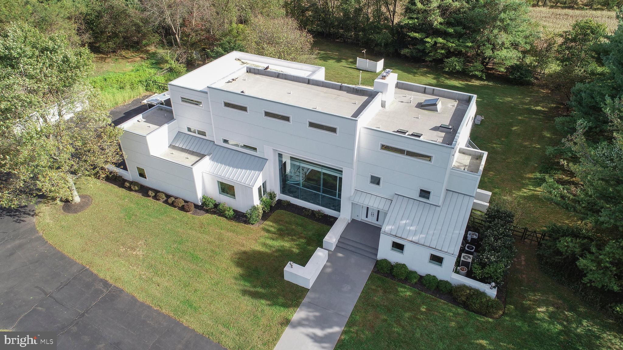 Introducing this extraordinary contemporary situated on 11 tranquil acres in Upper Makefield! This unique home offers 5 bedrooms and 5 full and 1 half bathrooms! Spectacular open layout with sweeping views of Bucks County from every room. The main gathering room features beautifully finished concrete radiant heated floors with 32 ceilings, floor to ceiling fireplace with metal surround and endless windows that create a dramatic effect to this area and provides a true connection to the outdoors. This space is the perfect place to display an elaborate art collection! Enjoy the state of the art gourmet kitchen with commercial grade appliances, wine storage, granite counters and a great breakfast area overlooking the private grounds. The family room has space for both TV entertainment and games. There is a fireplace and wet bar that makes spending time here quite enjoyable. The 5th bedroom & full bathroom are on the main floor and offer wonderful versatility if needed. This space also makes for a great home office. A custom helix radius staircase is a piece of art itself and leads to an upper bridge walkway leading to the master suite that includes large sleeping area, impressive walk-in closet with custom organizers and a luxurious bath with floating double vanities, large soaking tub and oversized step-in shower. 3 additional bedrooms and 2 full bathrooms complete the 2nd level. Finished lower level provides additional living space, game area, exercise room and full bathroom. The maintenance free deck stretches across the home and leads to the in-ground pool with a wooded backdrop creating a private feel amongst the 11 acres. Additional amenities include a 3 car attached and additional 3 car detached garage, only minutes to I-95 and downtown Newtown, panoramic views, Council Rock School District & low taxes.