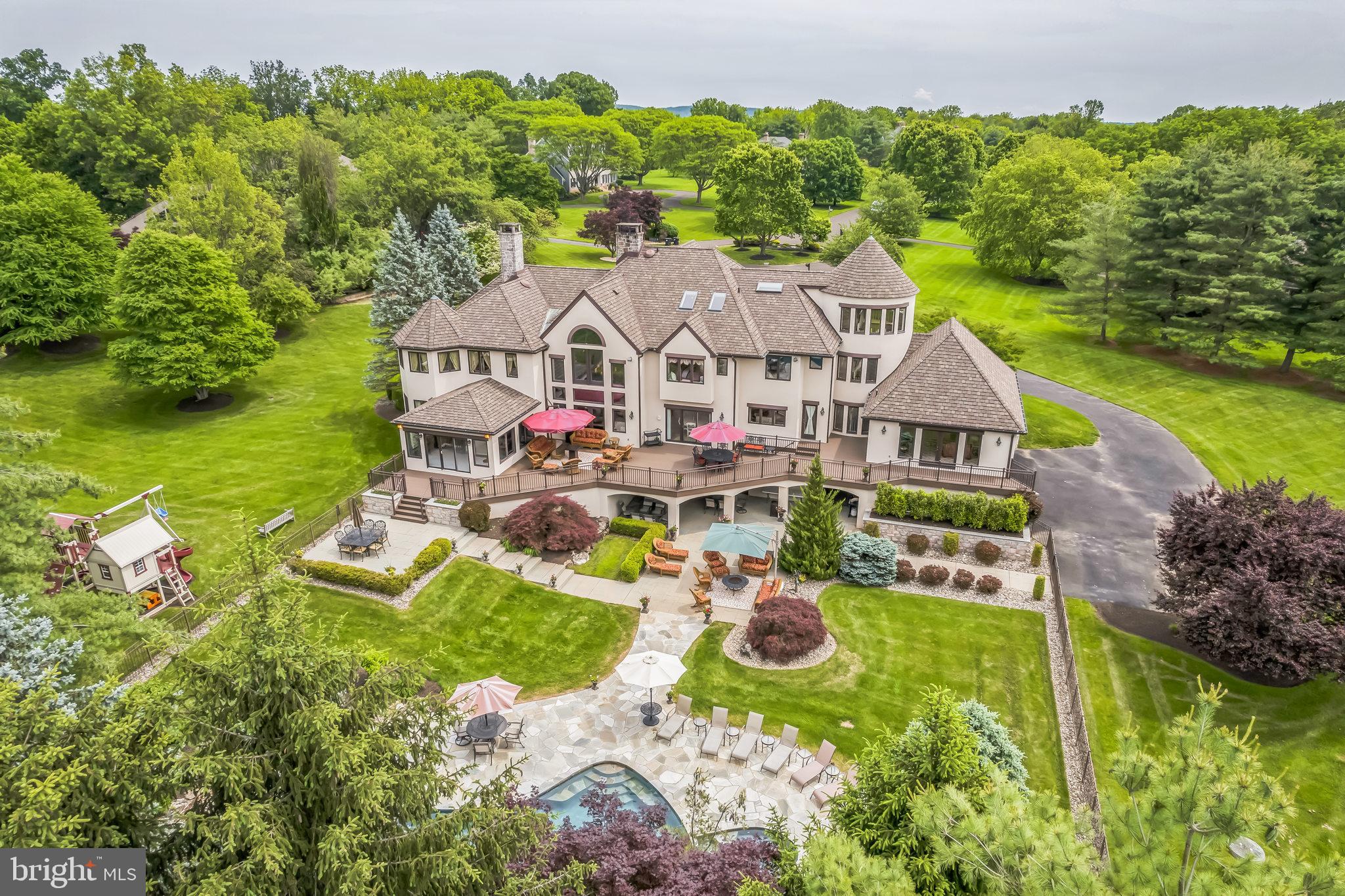 Welcome to 509 Wheatfield Lane, a truly extraordinary estate tucked away on 3.32 picturesque acres in the prestigious Timber Ridge community of Upper Makefield Township. Located at the end of a quiet cul-de-sac in the award-winning Council Rock School District, this impressive home blends architectural elegance, modern luxury, and resort-style amenities. A sweeping circular Governor’s driveway leads to a stately covered stone portico, setting the tone for what awaits inside. Enter the grand two-story foyer, where limestone flooring, a floating staircase, and intricate millwork make a striking first impression. To the right, the formal living room features hardwood floors, a two-sided stone gas fireplace, and a rounded alcove—ideal for a piano or seating area. Across the foyer, the banquet-sized dining room showcases extensive moldings, hardwood flooring, and a dramatic chandelier, perfect for hosting gatherings. The recently remodeled kitchen is a chef’s dream, designed for both beauty and function. Custom cabinetry with smart storage, a two-level center island, built-in espresso station, Wolf double ovens, upgraded cooktop, two cabinet-fronted Miele dishwashers, and two Sub-Zero refrigerator/freezers are complemented by limestone flooring, which extends into the dining area. An informal dining area with built-ins opens to a newly remodeled deck. Nearby, the well-appointed main floor laundry room includes a laundry chute from upstairs. The dramatic two-story family room features a soaring stone fireplace and a wall of windows that fill the space with light. Adjacent, the game/billiards room offers a second stone fireplace and curved alcove for cards or conversation. A spa room with built-in high-end spa adds a relaxing escape. The main level also features a conservatory with vaulted ceilings and access to the deck—ideal as-is, or easily converted into a first-floor bedroom suite or in-law suite. A beautifully updated powder room completes this level. Upstairs, the primary suite is a luxurious retreat with a serene sitting area in a turret, private office/sitting room, expansive walk-in closets, and a spa-like bathroom with jetted tub set in a dramatic alcove. Three additional bedrooms each have walk-in closets; two share a Jack and Jill bath, and one enjoys a private ensuite. Also on this level is a large multipurpose room, considered the fifth bedroom, currently used as an exercise room, and offering rough-in plumbing for a full bathroom. A private third-floor suite includes a spacious bedroom with sitting area, full bath, walk-in closet, and attic access—perfect for guests, in-laws, or an au pair. The finished lower level is built for entertaining, with a custom home theater (seating included), a second game room, full bath, sauna, and walk-out to the backyard. There’s also ample unfinished storage space in basement area. Step outside to your private resort: a heated in-ground pool with a winding rock "creek," thrilling water slide, and hidden cave. A separate spa area, multiple patios, and a covered outdoor lounge complete this outdoor oasis. Every inch of this remarkable property reflects luxury, quality, and thoughtful design. If you've been searching for an Upper Makefield estate offering privacy, prestige, and unparalleled lifestyle amenities—this is the one.