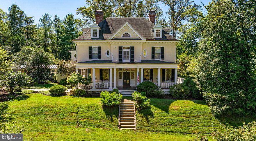 Nestled amidst nearly 3.5 enchanting acres, this picturesque Colonial Revival is simply captivating with its timeless, turn-of-the-century charm beginning at the stately wrap-around porch from which you can admire the stone gazebo upon the gently rolling hills encircled by lightly wooded grounds that create this perfectly private sanctuary. The interior features are equally impressive and emblematic of timeless workmanship showcasing the magnificent millwork, picture molding and gorgeous antique windows to the huge living and dining room pocket doors (with original cover panels in place) - a testament to meticulous preservation. The kitchen is a carefully curated masterpiece for the most discerning epicurean, boasting gorgeous white marble counters, a Wolf commercial gas range, custom-designed & hand-fabricated stainless steel and brass vent hood, SubZero 48” PRO series refrigerator, designer lighting, hand-cut marble shelves and more!  Absolutely exquisite hand-crafted cabinetry by a Pennsylvania Amish woodworker elevates the walk-in pantry, mudroom and primary suite dressing room, transforming usually utilitarian spaces into rooms of both beauty and exceptional functionality.  The second floor’s elegant primary suite is a sun-filled retreat featuring a gorgeous dressing area, bright and spacious bedroom overlooking the bluestone patio and pool plus a luxurious marble bath. In addition, three additional generously-proportioned bedrooms, two beautifully renovated baths and a convenient laundry room complete the layout. The fantastic third floor offers complete adaptability for your lifestyle preferences; with a large gathering area, two additional bedrooms, full bath and an impressive "seasonal closet," your options for customization are truly limitless. Celebrate the cooler autumn evenings with friends on the gorgeous bluestone patio! While a few ribeyes cook on the grill, share stories with your favorite beverage in front of the al fresco fireplace.  Come next summer, your gatherings will include a refreshing swim in the inground pool. Guests park with ease in the expanded parking area, and your short walk from the detached garage always stays dry under the connecting lighted breezeway.  The owner's visionary renovations have created more than just a house; it’s a haven where every day feels like a fairy tale, a place of understated elegance where cherished memories are just waiting to be made. This storybook property isn't a dream—it's your sanctuary!