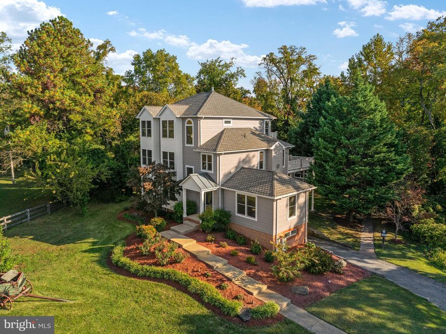 Welcome to 5108 Mountain Road, an exceptionally private 2.5-acre estate just steps from the entrance to exclusive Gibson Island, where timeless craftsmanship, modern luxury, and multi-generational living come together in a setting that is both elegant and unexpectedly serene. Reimagined in 2025 and offering more than 5,000 square feet of combined living space, this property invites you to experience a lifestyle rarely available  — one that unfolds with understated grandeur and a sense of quiet retreat that can only be appreciated through a personal tour. Nearly an acre of the property is beautifully cleared and manicured, creating an exquisite foreground for outdoor entertaining, while the remaining land is protected forest conservation, ensuring lasting privacy and a natural backdrop that changes beautifully with the seasons. Soft light filters through the trees, views of a neighboring horse farm add charm and tranquility, and the overall setting feels worlds away, yet effortlessly connected to daily life.  Inside the main residence, every detail has been curated with intention. Coffered ceilings, rich hardwoods, architectural millwork, and sun-drenched rooms create a refined warmth that flows throughout the home. The chef’s kitchen, with custom cabinetry, quartz surfaces, professional-grade appliances, and a bright breakfast room overlooking nature, is both a showpiece and a welcoming everyday hub. The living and dining rooms offer gracious spaces for gathering, centered around a fireplace and opening onto the composite deck. Two ensuite bedrooms on the main level provide sought-after flexibility, elevating comfort for guests, extended family, or those who prefer main-level living.  The upper level is entirely devoted to a remarkable primary suite — a retreat defined by scale, serenity, and thoughtful design. A spa-inspired bath, expansive walk-in closet, cozy fireplace, sitting room, and private office or gym create a sanctuary that feels both luxurious and deeply personal, while the balcony offers a peaceful perch for quiet mornings or soft, filtered sunsets. The lower level adds an additional bedroom, full bath, spacious den or media room, and access to the oversized garage.  Enhancing the property even further is the detached cottage — a fully independent residence that elevates this offering into something truly extraordinary. Complete with its own full kitchen, private bedroom, living room, full bath, and washer/dryer, the cottage is ideal for multi-generational living, long-term guests, an au pair, a caretaker, or a sophisticated home office or studio with absolute privacy. Very few properties in the region offer a secondary dwelling of this caliber, and its presence transforms the estate’s functionality and appeal.
Outdoor living is equally compelling, with a paver patio and built-in grill, lush open lawn, composite decking, and a long private driveway that easily accommodates large gatherings. The location — a quiet, desirable stretch of Mountain Road near Gibson Island and moments from Downs Park — combines prestige, natural beauty, and convenience, complemented by the highly regarded Chesapeake school district.
5108 Mountain Road is a property defined not only by its features, but by the feeling it evokes — a sense of arrival, of calm, of possibility. It is a home that reveals its finest qualities as you move through it, making an in-person tour essential to truly appreciate the craftsmanship, privacy, scale, and livability it offers. This is a rare opportunity to experience a lifestyle of quiet luxury and exceptional versatility in a setting that is undeniably special.