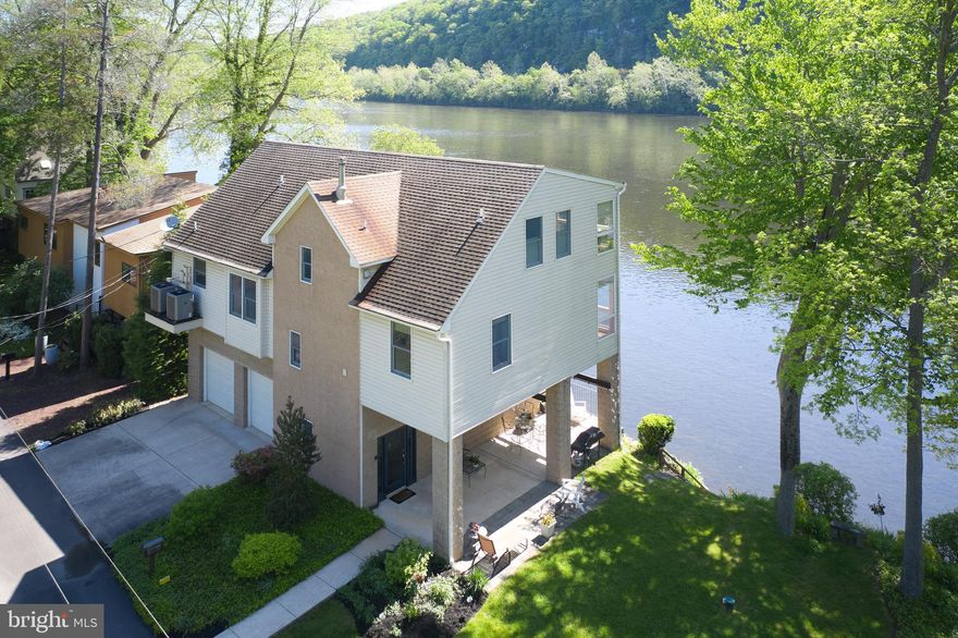 DelaView began as a 1930's fishing cottage that was rebuilt, circa 2006, into a stately home on the shores of the Delaware River.  The home, sited on Bridge 4, in Piperville, is considered one of the more coveted Bridges along the River.  The home is meticulously maintained both in appearances and in its landscaping. 
The interior foyer offers storage areas and the entrance into a two-car garage.  The elevator, which covers all three levels, is ideal for those looking for easy living and an elevated access to River views without having to climb stairs. The main level is an open concept with living room, informal dining and a chef's kitchen with high-end appliances.  This elongated space is basked in sunlight from the contiguous wall of glass that showcases one of the more magnificent River views. There are two bedrooms and two baths on this level…One is substantial enough to be a first floor primary bedroom suite.   The second level provides a large primary suite with stunning views of the River. The third bedroom suite contains a built-in desk space and an ingenious queen size "Murphy Bed" that is still ahead of its time.  Within this bedroom is a dry sauna perfect for relief from the Winter months.  This sauna can be easily converted in the future to a walk- in closet.  There isn't a room in this house where River views don’t take precedent.  The deck off of the main room is cantilevered and spacious and has a glass railing wall that purposely provides full views of the River in all directions.   The property, extends across the street to an additional two-car garage, lawn space for family gatherings and the home of a new septic system.  DelaView is a home that grew from a simple River cottage into a proper Riverfront home that is perfect for a weekend escape or a full-time residence.  It is rare that a property of this quality with this abundance of River shoreline comes on today's marketplace.  As the name "DelaView" aptly states, it will be a while before a home with these views of the Delaware become available again.  20 minutes to New Hope, 10 minutes to Frenchtown, N.J. and 90 minutes to Manhattan.  Showings can begin on Thursday, May 19th on.
