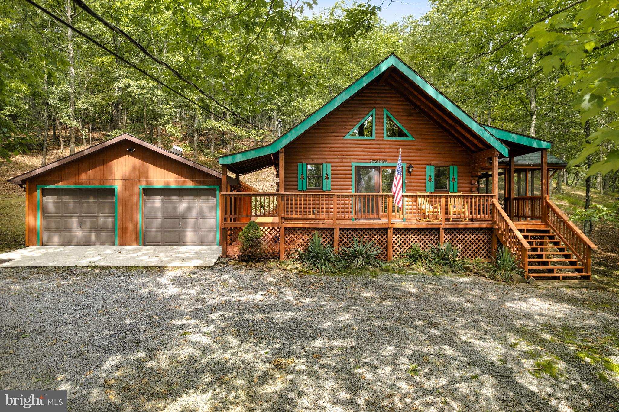Nestled within the serene & exclusive confines of The Crossings gated community in Paw Paw, this exceptional property offers more than just a home; it presents an immersive experience of cabin-inspired comfort & a seamless connection to the beauty of nature. As you arrive, be greeted by the rustic charm of a cabin-style exterior, a covered front porch, complete with natural wood accents & stone detailing & a detached 2-car garage. Step inside to discover an interior that effortlessly balances modern convenience with the warmth of a cabin retreat: vaulted ceilings, exposed wooden beams, and large windows create an airy & light-filled ambiance. The living area boasts a wood stove, perfect for cozying up on chilly evenings. The heart of the home, the kitchen, exudes a rustic yet elegant appeal. Featuring custom cabinetry, it offers both functionality & style. The lofted master bedroom gives you the view of it all, plus the main floor additional bedroom maintains the theme with wooden accents and tranquil space. The cabin experience continues outdoors with an expansive screened-in porch that beckons for outdoor relaxation & entertaining. Enjoy the crisp mountain air as you grill, dine, or simply unwind while surrounded by the sights & sounds of nature. Well cared for, plus upgrades: New roof last year, septic pumped 2021, new LVP flooring. The Crossings gated community offers exclusive access to amenities designed to enhance your lifestyle, like year round activities for the members. From trails that wind through the woods to the serene curves of the Cacapon River, perfect for fishing, swimming, or kayaking, you'll find plenty of opportunities to immerse yourself in nature. The Crossings is a wonderful HOA, however, they do NOT allow short-term rentals. Community offers, several river access points, a recreational pavilion, water entry for fishing, swimming & canoe launching, picnic, basketball, swings, and trails. This home is more than just a property; it's the embodiment of the cabin & nature second home theme; where comfort meets the great outdoors in perfect harmony.