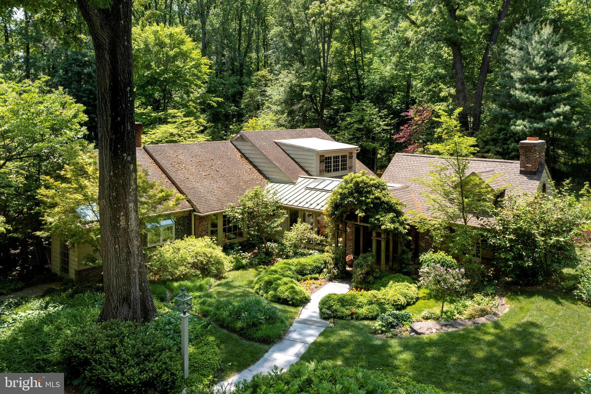 Expanded Cape tucked away on award winning arboretum like grounds in a highly desirable Whitemarsh Township neighborhood. The washed brick and cedar exterior blends with the exciting elements of the interior, including an open floor plan leading to spacious rooms, vaulted ceilings, main floor primary bedroom suite and several walls of windows providing streaming sunlight and panoramic views of the jaw dropping exterior grounds. A special property that truly offers indoor/outdoor living surrounded by an abundance of nature.
The long, circular drive surrounded by perennial gardens and heritage trees leads to flagstone walkways to covered front door entry. The entrance foyer with slate floors provides a tantalizing view of the stunning and spacious Great Room addition featuring soaring ceiling, radiant floor heat, architectural barn trusses, large wood burning fireplace flanked by custom built-ins and oversized windows providing breathtaking views of the exceptional grounds. The connecting Dining and Family Rooms also feature fireplaces and both rooms feature French doors to enchanting patios and ease of flow to the hub of the home, the Kitchen. Cooking and entertaining are a delight in the kitchen featuring added convivences such as long island, plenty of cabinetry, fine appliances and double sinks. The kitchen has side mudroom entrance and also opens to charming family room with dramatic vaulted ceilings, fireplace and neat overlook loft. The main floor also includes the Main Bedroom Suite wing with spacious bathroom including iron cast soaking tub, sky light, spacious walk in closet and separate study which could also serve as an additional bedroom. As a bonus, the Main Bedroom suite also features French doors leading to private flagstone patio. Also included on first floor: Butler's pantry with wet bar, beverage refrigerator and cabinetry - ideal for entertaining, breakfast room with oversized bay window, laundry room, mudroom off kitchen, main entry hall with exposed stone and more windows.
The second floor offers 3 spacious bedrooms, full bathroom with double vanity, numerous storage options and cozy loft with built in bookshelves overlooking the kitchen/family room area. The spacious upstairs layout offers endless opportunities to adjust living spaces, etc.
There is a partially finished Basement which includes a fitness area, workshop and mechanical room. In addition to the outstanding landscape, the exterio features a Two Car detached Garage and the most wonderful Gazebo tucked in the gardens. The location and exterior grounds are unparallel. The architecture masterfully blends the indoors to outdoors with many entrance ways, flagstone patios, covered verandahs and trellises. The inground swimming pool is a complete sanctuary surrounded by lovely specimen trees, perennials and accessed over wooden bridge walkway.
Property is located minutes to major arteries, 2 train stations, bustling town of Ambler, Germantown Academy campus & numerous connecting trails including Green ribbon and Wissahickon Trails.