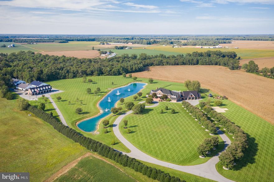 This first-time offering is a unique Eastern Shore estate that is the perfect marriage of serenity and style. No expense or detail was spared in building this custom family compound encompassing stunning indoor and outdoor spaces. The tree-lined circular driveway leads you to a gracious, brick manor home designed with large-scale entertaining in mind, starting with the two-story, double staircase foyer. The custom gourmet kitchen will satisfy any chef and provide a welcoming gathering spot for friends and family. Top-of-the-line appliances include Viking, Subzero, and Wolf, as well as an induction cooktop and icemaker. The butler's pantry is perfect for staging and storing everything you need to put on the perfect holiday gathering. For casual entertaining, The Grill Room offers a Viking beverage cooler, an infrared grill, and a Subzero icemaker. 
The spacious primary suite has a fireplace flanked by two doors accessing the outdoor balcony. The lavishly appointed primary bath features double vanities, a tiled shower, and a large soaking tub. The additional bedrooms within the main house are also en suite. Meticulous trim work, four fireplaces, and other special touches highlight the attention to detail throughout the home.
Once you step outside, you'll notice the same emphasis on entertaining and luxurious spaces. The amenities abound, starting with a 40x20 heated saltwater infinity pool with a swim ledge providing relaxation and fun throughout the summer and an ideal gathering spot for friends and family. The outdoor kitchen includes all you need for informal poolside gatherings. You can enjoy most seasons outdoors by using the covered porch, sun-drenched patio, or outdoor firepit on cooler evenings. 
Hobbyists, from automobile collectors to equestrian enthusiasts, will be delighted to make use of the many large accessory structures on the property. The nine-bay climate-controlled primary garage is ideally suited to showcase and preserve your museum-caliber automotive collection with CHI aluminum tinted glass and polished concrete flooring. This custom-built structure also features three-bedroom, two-bath guest quarters with a kitchen, living, and family room. Two separate, fully insulated, and climate-controlled garages (50 x 75) provide additional storage space with 12-foot overhead doors. These spaces could have many alternate uses, including first-class horse stables. Additional features include a 60-zoned irrigation system, Comcast Fiber internet, surround sound, a state-of-the-art security and surveillance system, and an 80 KW Generac generator. A truly exceptional property.