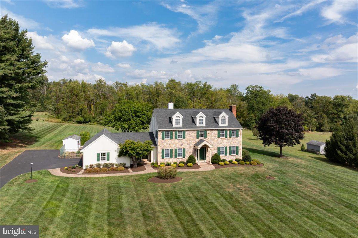 Built in 1971 by renowned local builder Bill Calhoun of Calhoun Builders, this five-bedroom, three-and-a-half bath home carries the timeless character, thoughtful design, and quality workmanship that Calhoun homes have been known for across generations. From the street, the home makes a commanding yet welcoming impression. Its stately stone façade, accented with crisp siding, green shutters, and three dormered windows along the roofline, embodies balance and tradition. The arched entry and brick chimney add warmth, while the sweeping lawn creates a sense of grandeur. For 51 years, the same family has lovingly cared for this home… celebrating holidays in the expansive dining room, gathering for summer afternoons by the pool, and filling its rooms with the milestones of family life. Offered now for the first time in more than half a century, the property reflects a lifetime of care and devotion. While the home is move-in ready, its next chapter invites the vision of new stewards… those who will appreciate its craftsmanship and history, while also embracing the opportunity to make it their own through thoughtful updates. Set on 2.3 acres along one of the area’s most desirable little-traveled roads, the property offers both serenity and accessibility. Just minutes from the heart of Doylestown the New Hope/Lambertville river towns and with excellent access to major routes, it combines privacy you want with the convenience you need. This is more than a house… it’s a tradition, a legacy, and an opportunity to continue the story of a beloved Bucks County home.
Inside, thoughtful details and practical upgrades abound. A bonus room opens to a generous 14’ x 32’ three-season porch, the perfect spot for relaxing or entertaining. The home offers two fireplaces for cozy evenings, along with a coveted cedar closet and the convenience of central vacuum. Comfort is assured year-round with two-zone heating, a whole-house fan, and the best of both worlds: oil radiator heat paired with central air conditioning. The side-turned 2 car garage is handily oversized.. Modern systems include a 220-amp electrical service, newer vinyl siding and replacement Anderson windows (2004), and a newer roof (2019). Outdoors, the property shines with an in-ground heated Norris pool (propane), an 8’ x 16’ storage shed, and landscaped grounds designed for both play and retreat.
Come see for yourself, fall in love with its timeless charm, and imagine the memories you’ll create here. Opportunity knocks! Don’t miss your chance to make this beloved Bucks County home your own and continue its story for generations to come.
