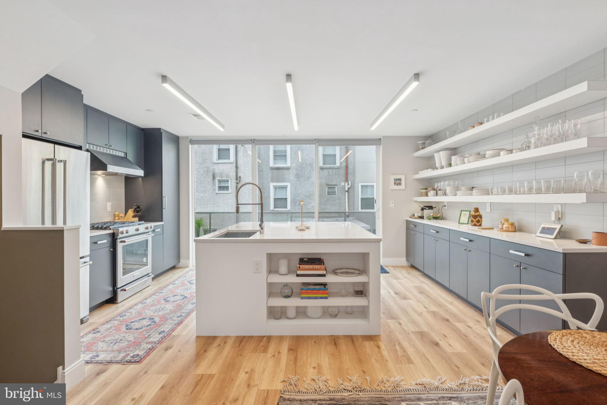 Basic? Not here. Skip the builder-box new construction hassles and punch lists, and enjoy details done well. Stunning 3-4 BR, 3 bath, 3000 sf designer townhouse right in the heart of booming Olde Kensington/Fishtown. The current owners have elevated this home with every luxury touch and thoughtful detail. Every surface has been freshly painted, custom lighting and dimmer switches installed throughout, California Closets added for smart, beautiful storage, and luxury window treatments from The Shade Store—including motorized blinds—for both style and privacy. Ceiling fans, smart dimmers, custom closets—even an EV-ready garage—are already in place.
The open living floor is flooded with natural light, featuring a spacious living room, dining area, and a chef’s kitchen with a massive quartz island, custom European-style cabinetry, and KitchenAid appliances—perfect for entertaining or everyday life. Upstairs, the primary suite feels like a luxury hotel, with skyline views, custom built-ins, and a spa-like bathroom with a soaking tub, oversized shower, and double vanity. Additional bedrooms are generously sized, and the finished lower level offers flexible space for a home office, gym, or storage.
Out back, the maintenance-free turf yard makes for the perfect doggy area or hangout spot. The rooftop deck takes it up a notch, with panoramic Center City views—and the thoughtful wet bar tucked into the hallway makes it ideal for morning coffee or evening cocktails. Practical features abound too: spray foam insulation, two-zone HVAC, a full security system, a garage with a 50-amp setup ready for your EV charger, and the remainder of its original 10-year tax abatement.
Best of all? You’re steps away from Philly’s hottest spots—Laser Wolf, Suraya, LMNO, Wm. Mulherin’s Sons, La Colombe, Evil Genius, Stateside Vodka, and countless boutiques, cafés, and creative spaces. This is where the city’s energy is right now, and this home puts you right in the middle of it. Upgrade your every day.