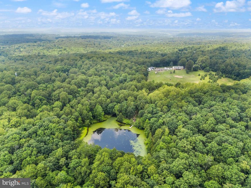 Elmore’s Farm – A Rare 223-Acre Gem on the DC Side of Warrenton

This sprawling 223-acre farm is an extraordinary opportunity to own a piece of Virginia’s rich countryside. Comprised of four separate lots being sold together, Elmore’s Farm, originally part of Hersch Farm,  offers limitless possibilities—from a private estate to a thoughtful subdivision—making it a truly one-of-a-kind property. Fauquier county letters on file with potential for subdivision into up to 17 buildable lots.

The land boasts 22 cleared acres surrounding a classic, expansive home built in 1970, perfectly blending peaceful rural charm with functional living space. The property’s hidden gem is the 2.5-acre stocked pond, teeming with bass, brim, and sunfish—ideal for relaxing afternoons and endless outdoor enjoyment.

Income potential is impressive here, with two separate apartments, each featuring private entrances and distinct styles and a monopole cell tower located on the far side of the property. 
The spacious basement apartment, completed in 2010, showcases durable luxury vinyl plank flooring, a cozy custom gas fireplace, a full kitchen, two large bedrooms, two full baths, and convenient full-size laundry. Above the three-car garage sits the charming “garage” apartment, finished in 2019, complete with gleaming hardwood floors, skylights filling the space with natural light, a full kitchen, laundry, two bedrooms, and a full bath.

The main home itself offers vast space and timeless character, lovingly maintained yet ready for your personal touch to transform it into a truly special family residence.

Adding to the farm’s functionality are two versatile outbuildings: a barn built in 1970 with 110-amp service and a sturdy metal roof, plus a pole barn added in 1979, perfect for storage, equipment, or livestock.

While some may see the true value in the expansive land, the potential here goes far beyond acreage. Whether you’re looking to build your dream estate, develop, or create a multi-use family farm, Elmore’s Farm invites you to imagine the endless possibilities on this cherished property