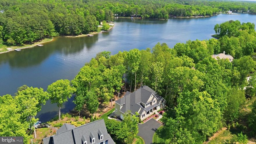 The epitome of waterfront living, this exceptional luxury Dream Home is nestled within Fawn Lake, one of Virginia’s most prestigious gated, resort-style communities.
Meticulously blending Modern Craftsman elegance with timeless architecture, this nearly new masterpiece by Warner Custom Homes offers over 8,300 square feet of exquisitely finished living space across three levels. Perched on a beautifully landscaped 1.50 acre peninsula lot with 367 feet of shoreline, the residence captures breathtaking panoramic water views while offering privacy, tranquility, and natural beauty. 
Designed to embrace the full allure of waterfront living, the remarkable Home showcases an effortless flow of light-filled spaces oriented to maximize the stunning lake views, creating an atmosphere where refined elegance and everyday comfort exist in perfect harmony. 
The thoughtfully designed floor plan balances expansive gathering spaces with intimate retreats, all enhanced by high-end upgrades and custom finishes throughout.
A soaring two-story foyer, anchored by a grand staircase with iron balusters, creates a striking first impression. Beyond, the spectacular Great Room features a dramatic wall of windows framing sweeping lake views, a two-story tongue-and-groove Coffered Ceiling, and a stunning limestone fireplace flanked by custom built-in media cabinetry.
The showstopping gourmet Chef’s Kitchen is beautifully appointed with custom cabinetry, granite countertops, a massive center island, and top-tier appliances, including a Wolf six-burner cooktop and separate Thermador refrigerator and freezer. Designed to accommodate both everyday living and grand-scale entertaining with ease.
Adjacent to the kitchen, a sunlit breakfast area with expansive windows offers captivating water views and seamless access to the oversized deck, perfect for seamless indoor-outdoor lakeside living.
The gorgeous formal Dining Room provides an elegant setting for entertaining, while a bright, inviting Morning Room with a wall of windows offers a  versatile space to relax and unwind.
The main-level Primary Suite is a true sanctuary, featuring a private sitting area with serene water views and a luxurious spa-inspired bath complete with a walk-in Roman shower, soaking tub, dual vanities, custom cabinetry, and an expansive walk-in closet with built-in organization and a dedicated dressing vanity.
Upstairs, a dramatic overlook captures sweeping lake views and leads to a second Owner’s Suite, along with two generously sized bedrooms with ensuite baths, each thoughtfully designed for comfort, privacy, and style. The open loft with a built in media center is perfect for movie nights. 
A spacious loft with a built-in media center provides the perfect setting for movie nights or casual gatherings.  The walkout lower level is equally impressive, offering exceptional space for entertainment and leisure. Highlights include a large recreation room with a custom wet bar and stone fireplace, a fully equipped gym, a home office, and an additional Bedroom suite with a full bath. A wall of glass doors opens to the outdoors, enhancing the home’s extraordinary seamless indoor-outdoor lifestyle.
An expansive deck off the kitchen, a covered porch, and a flagstone patio offer idyllic space to relax and entertain while taking in the lake views. The park-like grounds feature a stone pathway leading to the water’s edge and a private dock, providing direct access to boating, fishing, and paddleboarding. A convenient Lake-fed Irrigation System and Built-in Generator add comfort and peace of mind.  
The calm waterfront setting with ever-changing views, provides a perfect backdrop for creating lasting memories. Whether entertaining on a grand scale or enjoying quiet, everyday moments, this extraordinary residence offers an incredible opportunity to embrace the magic of Country Club life and the ultimate waterfront lifestyle in the prestigious and vibrant golf Community of Fawn Lake!