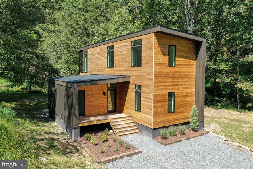 BRAND NEW CONSTRUCTION | Modern 3-Bedroom, 3-Bath -- Step into this sleek, modern sanctuary tucked among the trees. This brand-new 3-bedroom, 3-bath home rests on nearly two wooded acres. A serene stream-fed swimming hole on the property and the Lost River State Park trail system are right across the street. From the moment you enter the home, you’re embraced by light and views. Expansive Pella windows and glass doors open the home to the forest beyond, with the kitchen, dining, and living areas designed around walls of glass that frame the woods and gentle stream below. The sound of flowing water and rustling leaves sets a tranquil backdrop for daily living.  The primary suite is its own retreat, complete with a private balcony overlooking the stream and gentle waterfall—a perfect perch for morning coffee, quiet reflection, or simply taking in the stillness. Inside, the home pairs modern design and quality finishes: quartz countertops, custom cabinetry with floating shelves, durable LVP flooring, and ducted central heating and air. Three porches invite seamless indoor-outdoor living. Practical details make this retreat truly move-in ready: fiber optic internet, a private well with filtration system, a brand-new Electrolux washer & dryer, and professional landscaping and hardscaping already in place. Modern architecture meets the timeless calm of the Almost Heaven, West Virginia. This brand new home is ready for its first memories, first gatherings, and first moments of peace.  Further enhancing the experience of mountain living, an array of outdoor adventures await, with easy access to local markets, restaurants, boutique shops, and entertainment.  Click the video link and view the  Interactive Virtual Tour  to explore this incredible home will be added this week.