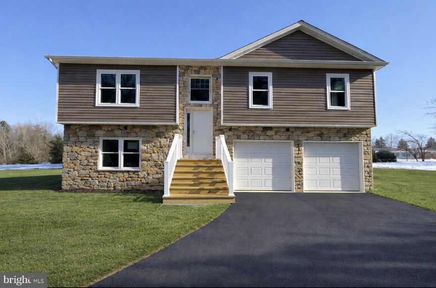 This well-designed new-construction home is currently under construction and will be ready in estimated April. Situated on a level lot with mature trees in Orchard View Estates, this home features 4 bedrooms and 3 full bathrooms with a functional and spacious layout. The exterior showcases vinyl siding with stone accents, recessed exterior lighting to accent the home, nicely paved new driveway, and a welcoming front entry with white vinyl railing and steps.Inside, luxury vinyl plank flooring runs throughout the home, including vaulted ceiling areas, enhancing the open and airy feel. Abundant windows throughout provide excellent natural light. The kitchen features white cabinetry with black accent hardware, a center island, a built-in pull-out pantry, and stainless-steel appliances.The primary suite offers a shiplap accent wall, with matching shiplap detailing in the primary bathroom behind the vanity. The ensuite bathroom includes a stand-alone soaking tub, a tiled shower, and black-accent mirrors and fixtures.The finished walk-out basement features 9-foot ceilings, a generous-sized bedroom, a large living or flex space, washer and dryer hookups, and exterior access through a 6-foot sliding door. Additional features include a 12x12 rear deck (no steps; steps available at an upgraded cost), an oversized 24x28 attached two-car garage, and a detached 17x24 one-car garage with electric and loft storage.Located in Orchard View Estates, the property offers a prime location with close proximity to the VA Medical Center,  Procter & Gamble, Amazon, and convenient commuter routes to Virginia, Maryland, and Washington, D.C.A quality new-construction opportunity in a highly desirable and convenient location.