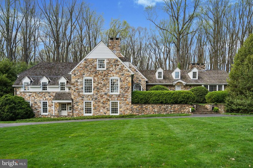This is your chance to own a classic & expansive Chester county farmhouse built & owned by an award winning architect. You arrive at the house from a quiet, winding road through the forest. The home is nestled into a hill, rambling as if built over time. At the top of the hill, a clearing opens to a broad expanse of lawn & a generous oval drive & second entry allowing ample parking. The exterior is made of old field stone carefully salvaged from old barn foundations to create massive proud chimneys & datestones.  A shake roof & clapboard & dormer details & period windows with stone surrounds add to the authenticity. The stone & clapboard give a clean & classic look.  
As you enter the home, up the stairs & through the mature boxwoods, you are greeted by an open foyer with detailed millwork of full raised panel walls & pilasters. Crowns & beams also highlight the authentic Chester County 18th century style. As you traverse the home, find wide random plank floors & bluestone floors throughout.  While the house is in detail authentically elegant, the 2006 construction allows many modern advantages such as large room size, high ceilings, large sweeps of tall windows & bays, in most rooms. Certain rooms like the garden room to the east & master bedroom to west have double height windows; two & three exposure per room are typical allowing light from morning to afternoon. Contemporary furnishings easily complement more traditional details. The house is long & allows for these exposures, so many places to congregate, dine & cozy up & read a book! The west end of the house features the main floor master with high ceilings & windows, as well as sofas for lounging & a wet bar, an updated walk-in closet & a bath with separate soaking tub & shower. Access from the master to the study provides a great option if you are working late. Four additional bedrooms on the upper levels share two full hall baths. The architectural details are too numerous to list & the plan creates memorable & unexpected features.
In contrast to the traditional moldings & tone walls, the east end of the house was recently renovated, transforming four independent rooms, kitchen, breakfast room, study & garden room, into one open flowing living & dining space. The center of the space is the huge stone two-sided walk-in fireplace & broad stone stairs that lead to the spectacular views from the walls of windows in the vaulted garden room & terrace beyond.  All molding was simplified & whitewashed, floors painted a stone gray giving the area a fresh modern farmhouse feel in the casual part of the house. A great place to entertain & enjoy! Entering from the casual foyer/mud room area, the garden level of the property offers a bedroom suite with attached full bath that is accessed by a private entry door from the front exterior & the lower casual foyer area & garage. Perfect for anyone needing to enter without using stairs, or for use as an au pair or in-law suite. It is connected, yet completely private.
Set within a large clearing of enormous Tulip trees, the grounds are composed of large sweeps of lawn, mature English boxwoods, Hollies, Rhododendrons & Norway spruce situated at a distance. Drifts of plantings provide seasonal color & there are many native ferns through out. The effect is a very green estate feeling, & is surprisingly low maintenance. Terraces are raised on walls & paths of blue & fieldstone have broad steps that lead to the lawn beyond. The topography offers a generous flat area for net & field games. The view of the landscape offers privacy in all directions.  One interesting detail is that the house sits at the highpoint between West Chester & Longwood; you can watch the coveted Longwood fireworks from the front terrace! Tucked away on a very low-trafficked street, this home is easily accessible to West Chester, Kennett Square, the Main Line, Philadelphia, Wilmington & a short Amtrack ride to NYC, plenty to do!