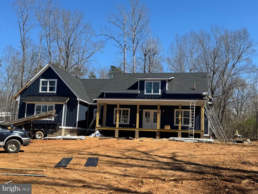 New construction by J.D. Goodman Builder, Inc.  with COVERED BOAT SLIP in Lighthouse Point on the private side of Lake Anna, offering assigned covered boat slip access and a refined modern farmhouse aesthetic. PHOTOS ARE OF A SIMILAR HOME. This 5-bedroom, 4.5-bath home is strategically designed for both everyday functionality and high-capacity entertaining, with sweeping vaulted ceilings anchoring the main living space and creating a strong architectural focal point. The oversized kitchen is the centerpiece of the home, engineered with scale in mind,  featuring quartz countertops, an expansive island, and a walk-in pantry large enough to function as a secondary prep/storage zone, aligning with current buyer demand for bulk storage and appliance concealment. The open-concept layout connects seamlessly to the family room, delivering clean sightlines and efficient flow. The primary suite is positioned for privacy and includes a well-appointed ensuite bath and generous walk-in closet. Additional bedrooms are thoughtfully distributed, including upper-level accommodations ideal for guests, multigenerational living, or flexible use (office, media, bunk room). Exterior execution is equally intentional: dark blue board & batten HardiePlank siding, contrasting trim, and a side-load garage enhance curb appeal while maintaining durability. Outdoor living is maximized with a 13’ x 30’ covered rear porch plus a matching 13’ x 30’ concrete patio, providing a substantial footprint for dining, grilling, and long-season use. Located within one of Lake Anna’s most sought-after communities, this property benefits from private water access, controlled neighborhood standards, and proximity to marinas, dining, breweries, and wineries—key lifestyle drivers for both primary residence buyers and second-home investors. Construction is actively progressing, with siding currently underway, positioning the home on track for its anticipated completion mid-May. The preferred lender is also offering closing cost assistance up to 1% of loan amount.