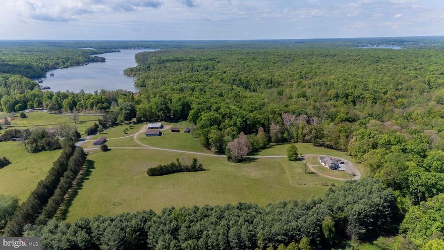 Set on 30 picturesque acres, this exceptional farm offers the perfect blend of open pasture, wooded privacy, and waterfront living on Lake Anna. With approximately 220 feet of shoreline and your own private boat launch, this property is a rare opportunity to enjoy both country living and lake life in one incredible setting.  The charming 3-bedroom, 2-bath home features an inviting open floor plan with hardwood floors throughout the main level. Designed to capture abundant natural light, the home offers a bright yet private setting throughout. A spacious great room centers around a beautiful brick fireplace with gas logs, creating a warm and welcoming gathering space. The separate dining room flows seamlessly into a large kitchen complete with abundant cabinetry, generous counter space, pantry, and breakfast bar—ideal for everyday living and entertaining.  The primary suite offers a peaceful retreat with private access to the deck, along with an attached bath featuring a jacuzzi soaking tub and separate tiled shower. Large secondary bedrooms provide plenty of space for family or guests. The full unfinished walkout basement offers endless potential, already framed with a rough-in for a future bathroom and materials on site to help bring your vision to life.  Outdoor living is just as impressive, with a large deck, screened-in porch with ceiling fan, and a patio area perfect for relaxing or hosting. The land itself is a dream—ideal for farming, recreation or simply enjoying nature—with a stream running along the back of the property, perfect for fishing, hunting, trail riding, or peaceful walks. There is an abundance of wildlife.  The mix of pasture and wooded acreage makes this property especially well-suited for horses, chickens, goats, or other livestock.  Multiple outbuildings accommodate animals or equipment, while the oversized workshop is a standout feature, complete with a hydraulic lift, kitchen area, and half bath—perfect for hobbyists or mechanics.  Additional highlights include a circular driveway, durable brick and Canadian cedar siding, lifetime GAF Timberline HD dimensional shingles (2011), a new HVAC system (2024), gas water heater for continuous hot water, and an owned 1,000-gallon underground propane tank.  This one-of-a-kind property truly has it all—acreage, waterfrontage, functionality, and comfort—offering endless possibilities for those seeking a private retreat or working farm at Lake Anna.  Property may offer potential for division; buyer to verify with the county.