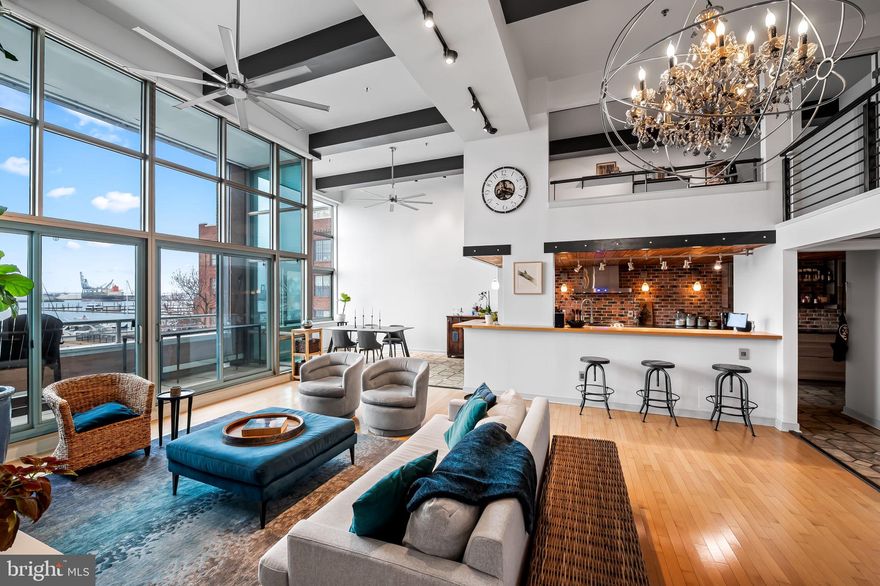 This direct waterfront contemporary loft is located in Canton Cove, a once abandoned warehouse on the harbor's edge.  The building was converted to 89 condominiums and incorporates a unique design of industrial and terraced architecture.  At 2,234 sq. ft., this extraordinary residence offers sweeping views from every room and boasts a floor plan designed to maximize an incredible sense of openness and style.  The home features on the main level an inviting entry, a dramatic great room and separate dining area with light-filled walls of windows, 18’ ceilings, and upgraded lighting.  The sleek gourmet kitchen is a cook’s dream with the expansive quartz countertops, stainless appliances, gas cooking, stylish brick backsplash and accent wall, original wood ceiling, and a breakfast counter.  The striking primary en-suite bedroom and bath are conveniently located on the main level and include a walk-in closet, soaking tub, and separate shower.  A laundry room with substantial additional storage area and powder room are also located on this floor.  The mezzanine loft includes two additional spacious bedrooms with walk-in closets, a hall bath with a large shower, a balcony overlook, and utility room.  Additional features include a steel and wood staircase, maple hardwood and ceramic tile flooring, original wood ceilings in various areas, ample closet space, and custom window shades. The HVAC was replaced in 2024.  The private balcony, accessed from the great room and primary bedroom, provides the perfect space for casual dining, relaxation, or just enjoying the spectacular views. Two assigned parking spaces, one in the garage #45, and one in the secure parking lot #3, convey.   Building amenities include 24-hour front desk staffing, security, gas, water usage and basic cable service.  Residents and their guests can also enjoy and relax on the community's massive roof terrace with spectacular views of the city, Harbor, Ft. McHenry, and fireworks.  The condominium complex is located in the heart of Canton's residential and commercial areas and is within walking distance to Canton Crossing, "The Square", restaurants, bars, and parks.  Within proximity are Downtown Baltimore, Harbor East, Fells Point, Brewers Hill, Johns Hopkins and U of M Medical Campuses, institutions, and major highways.