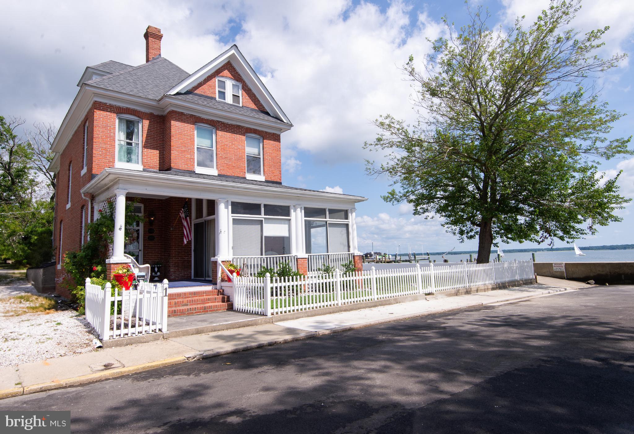 Experience the best of the Eastern Shore in this beautifully preserved 1918 home, ideally located in Cambridge’s Historic West End District along the Choptank River. Enjoy walkable access to downtown, the Yacht Club, two waterfront parks, and nearby boat ramps—truly a lifestyle rooted in history, nature, and community.
Take in spectacular sunrises and vibrant views of sailing events and waterfront races like Eagleman and Ironman—all from your expansive screened wraparound porch.
Inside, you’ll find over 2,200 sq ft of timeless character blended with modern comforts. Original wood floors, pocket doors, and classic woodwork pair beautifully with panoramic water views from nearly every room. The spacious foyer leads into a cozy living room and a formal dining area that opens to the enclosed porch—perfect for entertaining year-round, complete with sliding glass doors and electric heating.
The bright kitchen features white cabinetry, custom built-ins, and a central island peninsula that flows into the sunlit River Room—an ideal spot to relax and take in the ever-changing river views, from skipjacks to osprey.
Upstairs, the primary suite includes dual vanities, a walk-in shower, and ample closet space, along with a flexible bonus room—great for an office, extra guest space, or private retreat. A second bedroom also offers stunning water views and a private bath. A walk-up attic adds even more potential.
Outside, enjoy over 120 feet of protected waterfront, a double-sided dock that can accommodate a 37-foot boat, and a detached garage with storage and workshop space. Off-street parking rounds out the conveniences of this rare waterfront gem.
Don’t miss the chance to own a piece of Cambridge’s rich waterfront history—schedule your showing today.