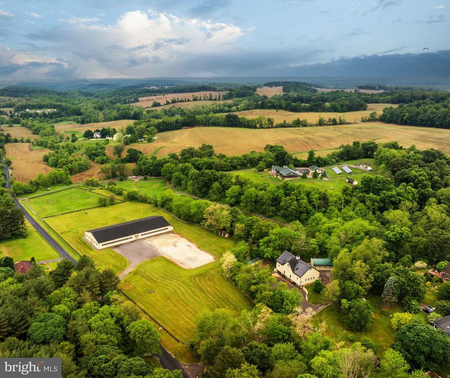 Live authentically. Cedar Crest Farm. Discover a sanctuary where authenticity meets tranquility. Embrace the road less traveled and look forward to meandering through serene country lanes, enveloped by towering trees, leading you to your haven. You have arrived at your equestrian estate. Channeling an enduring Jackson Hole Mountain aesthetic, perched on 19.67 enchanting acres with panoramic big sky views...you won't want to leave. 
Be greeted by a soothing neutral palette and exquisite millwork that showcases superior craftsmanship throughout. Expanses of glass and open spaces frame the beauty surrounding you. Step outside to a 140-foot wraparound covered loggia that terraces to an elaborate 80-foot-long incredible deck, perfect for taking in breathtaking sunsets and sunrises. Enjoy leisurely evenings under the stars on your stunning terrace. The tranquil fountain sculpture, "Coming Together", by Aristides Demetrius, is as remarkable as it is soothing. Let scintillating conversation flow freely by the cozy fireplace and inviting fire pit—ideal for gatherings and quiet reflection alike.
Behold the party barn of all party barns. Three stories of jaw-dropping exposed beams, soaring ceilings and a plethora of possibilities. Complete with its own kitchen, bath and dedicated bedroom space.
For the riding enthusiast, there's an impressive 200x90, 18,000 square foot indoor riding arena where the lights come on instantly. There are mirrors covering the back wall and the walls are canted for safety. No detail is overlooked. The footing is a comfortable mix for horses including bits of tire. Ride effortlessly from the indoor to your outdoor riding arena, complete with jumps and jump storage. There is also a full cross-country course on the property. This includes coops, bank jumps, tables, corners and everything a rider desires. Eight stalls in the bottom barn, one of them currently used as the wash stall equipped with hot and cold water and heat lamps. The upper barn offers a multitude of possibilities due to its spacious and versatile nature...it currently has two stalls. Ample garage space at the house and down at the barn could make an easy conversion to more stalls if needed. The hay shed holds 500+ bales of hay. Ideal for anyone looking to enjoy and utilize a well-equipped equestrian facility, whether for personal use and beyond. Additional features include run-ins and an accessible stream through the bottom fields with a charming bridge. Indulge in luxury with a lap pool and hot tub, providing year-round relaxation and wellness. The lush greenery encircling the property enhances the sense of seclusion and peace. This property is not just a farm, but a lifestyle—a place where every day feels like a retreat. Cultivate your existence. The art of uniting human and home.