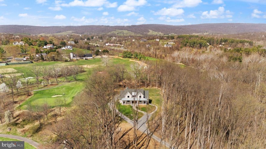 Modern Farmhouse Property in Beautiful Western Loudoun County

 MAJOR PRICE REDUCTION! NOW OFFERED AT $1,899,000

This exceptional Nearly New Custom Home offers refined luxury and privacy on an elevated 5.2-acre wooded homesite bordered by protected Open Space and Stoneleigh Golf & Country Club. The setting is peaceful and scenic, with seasonal mountain views, mature trees, and a tranquil creek. Located just 1/2 mile from Round Hill and minutes to Route 7, the property provides both seclusion and convenience, along with no HOA, underground utilities, and high-speed Verizon Fios.
A private quarter-mile driveway leads to the stone and Hardi-Plank exterior, where the wraparound porch and curated hardscaping create a striking arrival. Inside, the home features 10-ft ceilings on the main floor and 9-ft ceilings on the upper level and basement, along with White Oak wide-plank wood floors, soaring beamed accents, a dramatic floor-to-ceiling stone gas fireplace, and a formal library with French doors. Large windows and an open layout highlight the natural surroundings and create a warm, elevated atmosphere and lovely views from every room.
The main-level Owner's suite offers a luxurious retreat with a custom closet including an island and window seat, a spa bath with heated floors, oversized walk-in shower, soaking tub, and toilet closet. Direct access to a covered porch with a gas fireplace extends the suite into a year-round outdoor living space.
The chef's kitchen is equipped with a Wolf range, Subzero refrigerator, Bosch dishwashers, Designer Level 5 Granite island, ceiling-height cabinetry with lighted glass uppers, walk-in pantry, and Butler's pantry. The main level also includes an open elegant dining area, a corner pocket office, the Great Room with Stone Gas Fireplace that leads to the rear covered porch, a full tiled bath and walk-in shower, and a mudroom/laundry with built-ins and access to the 3-car garage.
Upstairs offers a loft and media area with a wet bar and beverage fridge, plus three bedrooms-one ensuite and an additional full hall bath, which can be shared by loft area visitors and the two extra bedrooms.
The fully finished basement features high ceilings and includes a fifth ensuite bedroom, a hobby room with workbench, a large family room with an entertainment bar and full-size refrigerator, and a walkout to the custom patio and hardscape path to guest parking.
Premium upgrades include custom built-ins, designer window shades, High-End Systems, deluxe appliance and paint packages, upgraded blown-in insulation, 8 Ceiling Fans, a 500 GAL buried propane tank, and a whole-house generator. Close to Purcellville, Leesburg, wineries, breweries, parks, pools, and shopping, with Dulles Airport approximately 35 minutes away.

Current school district includes Woodgrove High School, Harmony Middle School, Mountain View Elementary. Check for updates, as districts change occasionally.