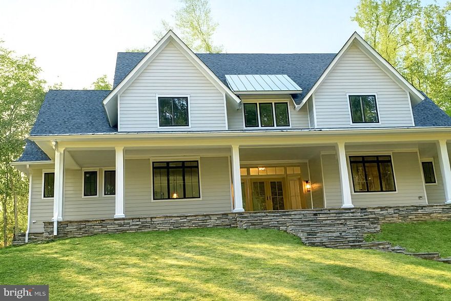Coming Soon to Western Loudoun County Picture Perfect – Supreme Privacy – Great Location!
Introducing an exceptional Modern Farmhouse, gracefully situated atop a picturesque 5.2-acre wooded homesite. This distinguished residence offers a harmonious blend of refined luxury and tranquil country living, providing an atmosphere of unparalleled comfort and exclusivity.
The property ensures utmost privacy, bordered by protected Open Space and the prestigious Stoneleigh Golf and Country Club.  Everyone will appreciate the captivating seasonal mountain vistas, woodlands and creek views. Free from HOA constraints and equipped with high-speed Verizon Fios, the location combines serenity with exceptional connectivity—found just a short distance from Round Hill and Route 7.
Approaching via the private quarter-mile driveway, one is welcomed by an impressive stone and Hardiplank farmhouse, complemented by an expansive wraparound porch ideal for relaxation or sophisticated entertaining. Upon entering the home, the open-concept interior is bathed in natural light, and features soaring beamed ceilings, a striking floor-to-ceiling stone fireplace, and wide-plank natural wood flooring that imparts a sense of warmth and grandeur. As you enter, you will find a formal library with shelving, cabinetry and French Doors. The sumptuous first floor Owner's suite includes a separate Custom Closet with Island and Window Seat, Ensuite Bath features heated floors, tremendous walk-in shower, soaking tub, toilet closet and large vanity with Double sinks and Lighted mirrors. The cozy bedroom leads to covered back porch with fireplace, perfect for a quiet intimate evening. 
At the heart of the home lies a chef’s kitchen of remarkable design. Outfitted with premium appliances such as a Wolf range, Subzero refrigerator, and Bosch dishwasher, this kitchen presents a generous center island with granite countertops, perfect for culinary pursuits and gatherings. 10' cabinets reach the ceiling with lit glass-front uppers, unique tiles, and custom painting that combines style with utility. There is a generous walk-in pantry, along with a large Butler’s pantry, offering plenty of storage and prep space for hosting gatherings.
Providing convenient side access from the three-car garage, the spacious mudroom and laundry area features integrated seating and ample storage solutions. Adjacent to the kitchen, a discreet pocket office offers a tranquil workspace with built in cabinets and abundant natural light. The adjoining dining room distinguishes itself with a beamed ceiling and generous proportions, ideal for hosting elegant gatherings in a memorable atmosphere. The main level also includes a cozy Great Room that opens onto a covered back porch finished with stamped concrete and flagstone, complemented by a stone gas fireplace. A full bathroom with a walk in glass shower and granite countertops serve both guests and family.
The second floor includes media and loft spaces with a wet bar, beverage fridge, and ceiling fans.  The third bedroom features an ensuite bathroom with a walk-in shower, and the other two bedrooms share a large hall bathroom.
The finished basement offers plush carpet, a fifth ensuite bedroom with bath, a hobby room, a large family room with entertainment bar, cabinets, a full-size stainless refrigerator, and a sitting area that opens to a walkout custom stone patio. Once outside, a wonderful walkway circles to front guest parking area. 
Some upgrades sure to appeal to Buyers are Custom Window Shades, a Deluxe Appliance Package, Deluxe Paint Package, a Whole House generator system, Upgraded Blown-in Insulation Package and much more.
Conveniently located 1 mi to Round Hill, Virginia, and 5 minutes to Purcellville with dining establishments, shopping, parks, pools, and schools nearby. Dulles Airport is 35 minutes away via the Greenway. Local schools listed as follows: Mountain View Elementary, Harmony Middle School, and Woodgrove High School.