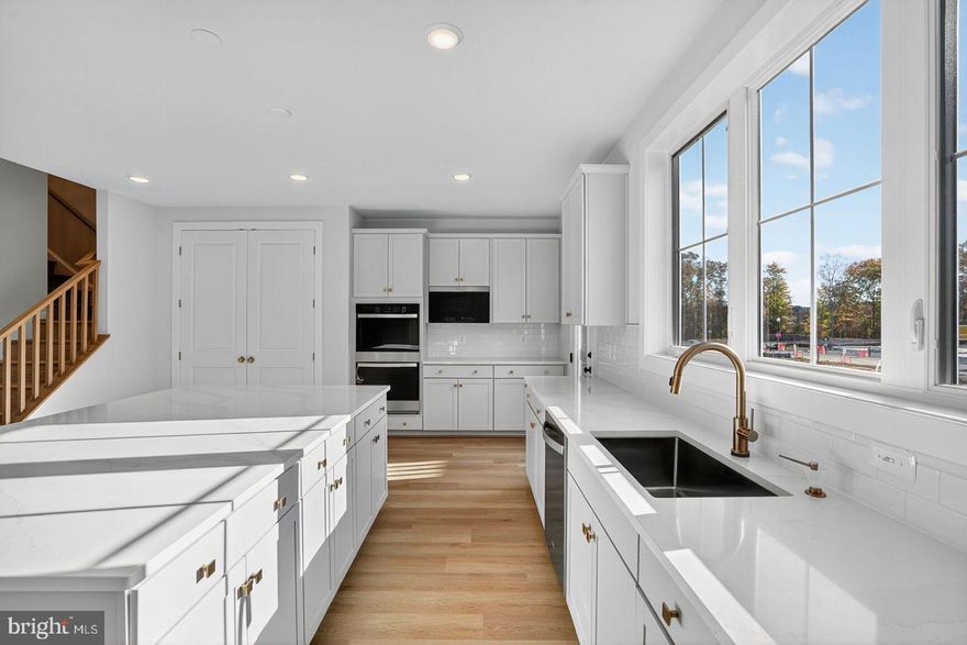 The main level offers a bright and open layout with a generous great room, dining area, and a rear kitchen that seamlessly connects to the outdoor living space. The chef-inspired kitchen offers an expansive island with Calacatta Gold quartz countertops, Brellin Frost cabinets, stainless steel appliances, and gold hardware. Upstairs, the primary suite impresses with its spacious walk-in closet and a spa-like bath featuring quartz countertops. Two additional bedrooms, a full bath, and a conveniently placed laundry room complete the second floor. The finished lower level provides even more living space with a bedroom and an additional full bath.