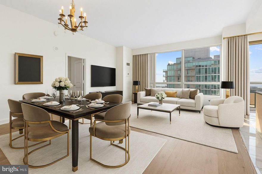 Perched high above the Delaware River, this stunning Southwest-facing corner residence at Waterfront Square offers sweeping Benjamin Franklin Bridge, Delaware River, and City skyline views from every angle.  R2203 Effortlessly blends bright modern interiors with a private balcony that captures some of the most dramatic sunsets in Philadelphia. The moment you enter, the home feels spacious, fresh, and refined, beginning with a striking foyer finished in glossy white-and-gold Calcutta tile that continues through the kitchen, dining area, den, and laundry zone—instantly elevating the home with a polished, luxurious aesthetic. From the foyer, the space opens to a grand living area wrapped in floor-to-ceiling windows that flood the home with sunlight throughout the day. Brand-new wide Hickory–style luxury vinyl plank flooring adds warmth and sophistication, running throughout the living areas and bedrooms in a seamless, modern flow.

The open kitchen enjoys exceptional natural light and is anchored by a large granite island ideal for dining or entertaining. Stainless steel appliances, rich wood cabinetry, and a full tile backsplash offer timeless functionality, while the Calcutta tile flooring gives the kitchen and adjoining dining space a crisp upscale feel. Just off the kitchen, a sunlit den enclosed in floor-to-ceiling glass creates a captivating nook for breakfast, reading, or a boutique-style sitting area—made even more dramatic by the uninterrupted river panorama directly outside the windows. Sliding doors lead to the home’s large private balcony, a standout feature offering incredible space for lounging, dining, and taking in breathtaking riverfront and skyline views. Whether enjoying soft morning light or unforgettable sunsets, this balcony truly extends the living space into the open air.
A spacious hallway leads to the laundry area, outfitted with Bosch appliances and generous built-in shelving. A conveniently located powder room enhances everyday living. Both bedroom suites are serene and generously sized, each enjoying its own walk-in closet, an additional reach-in closet, and a linen closet—providing exceptional storage rarely found in city condominiums. Combined with the dedicated coat closet at the entry, the home offers a total of seven closets, allowing for effortless organization throughout.
The primary bedroom is a true retreat, wrapped in five floor-to-ceiling windows that frame sweeping river and skyline views while filling the space with glowing southwest light. Its en-suite bathroom is a spacious four-piece design, featuring a double floating vanity, a large glass-enclosed shower, and a separate deep soaking tub surrounded by warm stone tile. The secondary bedroom also enjoys its own four-piece en-suite bath, mirroring the same generous proportions and clean, modern finishes.
Waterfront Square Condominium & Spa is Philadelphia’s premier gated waterfront community, offering 24/7 guard and gate security, concierge. Residents enjoy resort-style amenities including an indoor pool and hot tub with river deck, fitness center, sauna and steam rooms, massage suites, and community lounges. The three-level garage supports Philadelphia’s largest green roof, and landscaped gardens across 9.5 acres of manicured riverfront grounds. On-site management and an advanced closed-circuit security system ensure peace of mind, while Global Limousine shuttle service provides weekday transportation to and from 30th Street Station.