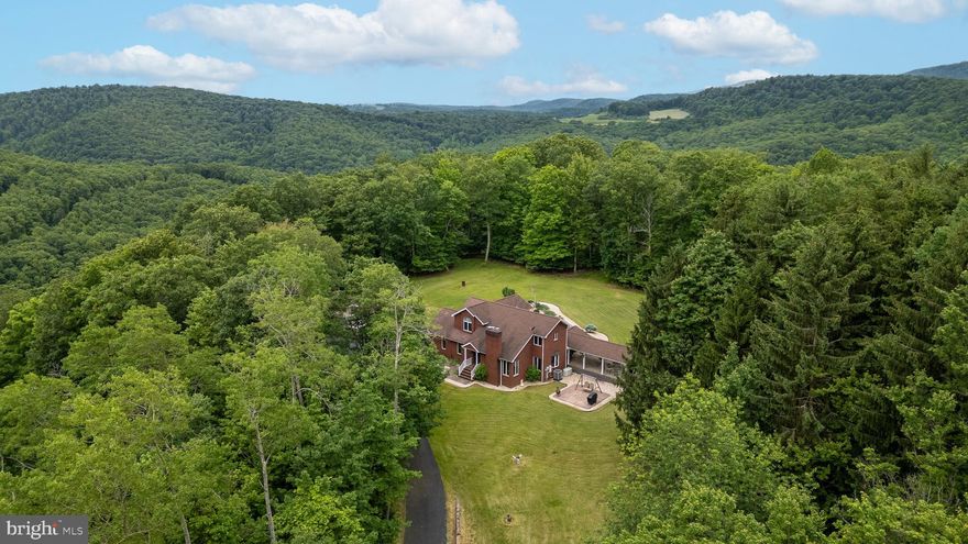 Take a journey to a secret tucked away at the top of the mountain!  A paved private driveway takes you 1/3 mile through a nature hideaway of wildlife and PA's woods to a 2-story brick home awaiting you at the top.  Nice flat lot & yard located almost in the middle of your own 40-acre parcel gives you permanent rights to seclusion, views, tranquility, but with all the city amenities.  Unwind in the back yard landscaped with waterfalls, 2 ponds with goldfish & Koi and a bridge over the pond for feeding the fish. A covered patio with an adjoining 16 x 40’ covered pavilion invites you to outdoor relaxation and entertainment at their best.  Lights, ceiling fans, sounds of waterfalls and nature's choir create a state of peace.  The interior of the home was completely remodeled in 2013-14. Ceilings in 1st floor are hickory tongue-n-groove for a "Switzerland" feel.  Gourmet kitchen with Thermador gas range/griddle and hood for food prep, double wall ovens, cherry cabinetry with custom woodwork, soft close, granite countertops and a granite sit-down breakfast nook.  The living room/great room has a 17' angled ceiling with brick fireplace.  Upstairs the 14 x 18’ owner's suite has Dutch doors out to a large balcony overlooking the back yard and with steps to the patio.  There are two additional bedrooms and a full bath on that floor.  The lower level is a hidden gem with a full-fledged "Saloon" of your own!  A wet bar with copper bar top, bar stools, large mirror lights and ready to "order up" and a large, finished area with another beautiful fireplace.  There is also a room for cool storage, a full bath, and a laundry room.  There is an oversized 2-car attached garage with 2 storage areas plus a detached 24' x 26' garage that is drywalled, painted, and versatile.  You will just need to see this one to appreciate the beautiful setting!