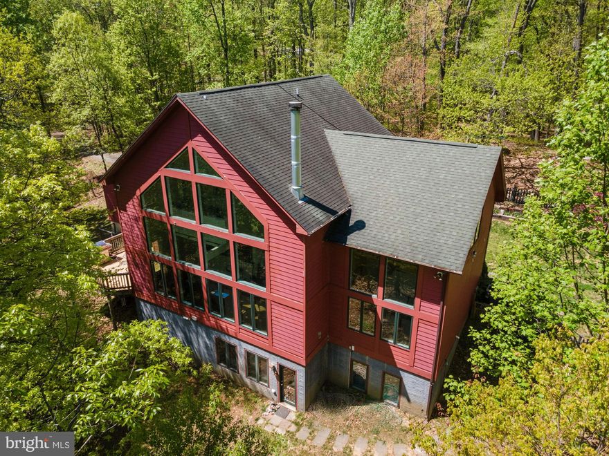 IMMEDIATE DELIVERY!  Bring offers.  Welcome to the “Barn Red House” in Leesburg. This private retreat was built to be part of nature and was inspired by Deck House, Circa 2000.  This unique, custom-designed home is a true architectural gem built by local builder, Jay Cecca.  The home features a breathtaking two-story wall of windows that floods the interior with natural light and offers stunning views of the surrounding landscape. Nestled on 10.26 mostly wooded acres, this property provides a serene and secluded haven. The kitchen was updated in 2018 with stainless steel appliances and leather finish granite counters. The skylight brings light into the center of the kitchen where you can take in those beautiful outside views from the windows while preparing meals.  You'll find five spacious bedrooms, perfect for family and guests. The fully finished basement is a versatile space, complete with a recreation room for entertaining, a music studio for the budding artist, and dedicated hobby areas to suit all your creative passions.  Outside there is a fenced area to play. There is a covered sand box and your very own tree house.  On lazy days you can sway in the hammock under the trees or enjoy coffee on the deck and listen to the birdsong.  Don’t miss your chance to own this extraordinary property.  Antiques shopping, wineries, specialty food and farmers markets are close by.  Easy access to the Marc train to DC. Dulles Airport is about 25 minutes away. Love Where You Live!
