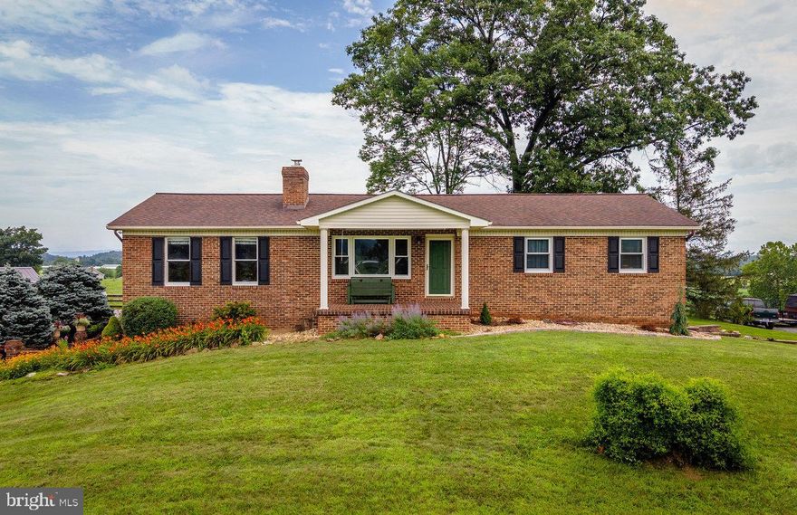 Spacious brick ranch on 2.5 acres perched on a hilltop with glorious views! Main level includes 13x18 living room with wood-burning stove, brick hearth, beadboard ceiling, and hickory floor, 12x19 eat-in kitchen with stainless appliances (including gas range) paneled wainscoting, and hickory floor, home office nook, 15x17 dining room with oak floors and exposed brick, 11x13 sun room with beadboard ceiling and tile floor, hall bath, three bedrooms, including owner's suite with 10x11 sitting room, 12x18 bedroom, walk-in closet, completely remodeled bathroom with heated tile floor, two separate vanities, tiled shower with glass enclosure! Basement level walks out on two sides, and includes huge rec room with engineered wood floor and gas stove, bonus room, laundry room, 15x24 multi-purpose room with tile floor and large set of built-ins, 272 sq. ft. workshop with double doors to exterior, 7x14 storage area. Covered front porch AND large brick patio off basement level. Gorgeous landscaping, paved driveway, and three sheds. Don't miss this fantastic opportunity for country living!
