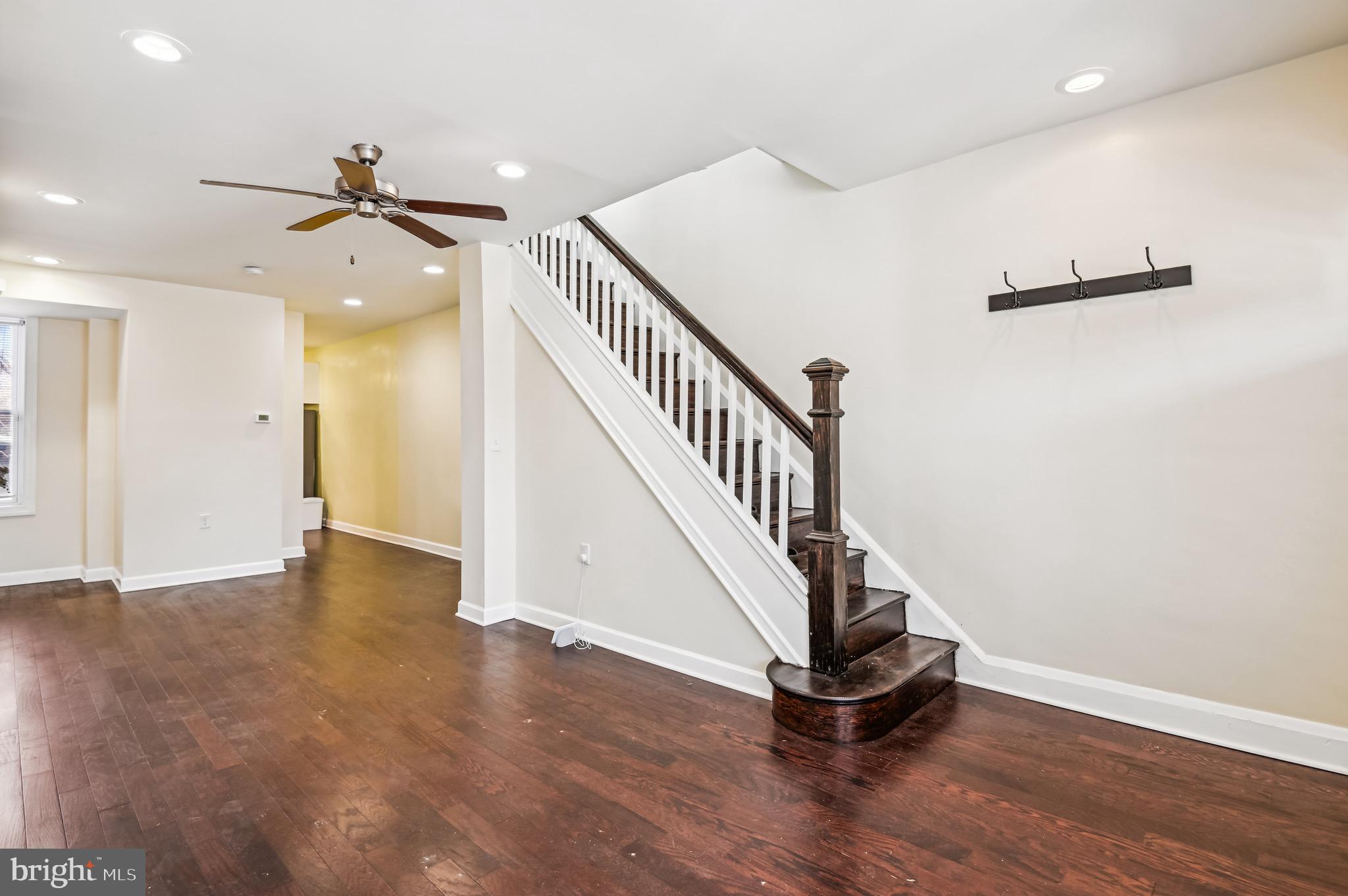 This charming townhouse at 19 N Hilton, Baltimore offers 3 bedrooms, 1 full bathroom, and 1 half bath. Upon entering, you'll notice the beautiful hardwood floors and recessed lighting that flow throughout the home. The main level begins with a cozy living room, complete with a ceiling fan and large windows that let in plenty of natural light. The dining room is adjacent to a convenient powder room and leads into the updated kitchen, which features sleek stainless steel appliances, a white subway tile backsplash, a gas range, plenty of white cabinetry, and direct access to the lovely backyard. The primary bedroom is spacious and highlights the home's hardwood flooring. The upper floor also includes two additional roomy bedrooms and a stylish full bathroom with modern tiling and finishes. The lower level is unfinished, offering endless possibilities for customization or use as a laundry area. Relax with a cup of coffee on the large front porch, overlooking the fully fenced front yard. This home is ideally located with easy access to public transportation, nearby shops, dining, and parks, offering a perfect blend of historic charm and contemporary convenience.