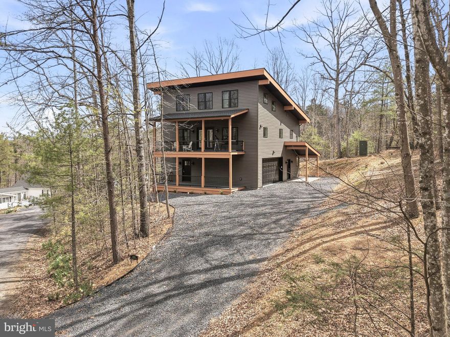 New Price! "Greenview Landing" Mountain Elegance with Versatile with 2 Living Spaces. Nestled in the heart of the mountains, this home offers a rare blend of contemporary design and alpine serenity. Permitted for 5-bedroom short term rental with the county. Spanning three thoughtfully designed levels, the residence is as functional as it is stunning. The lower level lives like a private apartment, complete with its own entrance and parking area, full kitchen, living and dining area, bedroom, full bath, and laundry hookups—ideal for guests, extended family, or rental potential. A covered patio adds a quiet outdoor retreat. Upstairs, the main level welcomes you with custom floors and sleek modern fixtures throughout. The open-concept kitchen, living, and dining area is anchored by a striking electric fireplace and flows seamlessly onto a covered deck—perfect for entertaining or unwinding with mountain views. Two spacious bedrooms each feature en-suite baths, and a stylish half bath and full laundry room round out the floor. The top level offers two additional bedrooms and a full bath, providing ample space for family, work-from-home flexibility, or creative use. There is an area for storage also! An oversized two-car garage and a gently sloped driveway with generous parking make mountain access effortless. This home is a rare opportunity to enjoy the tranquility of mountain living without sacrificing modern comfort or convenience. Seller to offer one year warranty valued at $600.00. Property comes with state of the art video surveillance monitoring system. Floors are Bruce Natural Hickory and siding is NDX premium vinyl siding. Bryce Resort is 7 minutes away and offers the following: small airport, library, dog park, indoor pool, outdoor pool, lazy river, pickleball, tennis, playground, 18 hole golf, course, mini golf, lake, mountain biking, skiing, snowboarding, ice-skating rink, and restaurants. 1.5 hours from NoVA. There is a farmers' market on Wednesdays during the summer. Call now for an appointment.