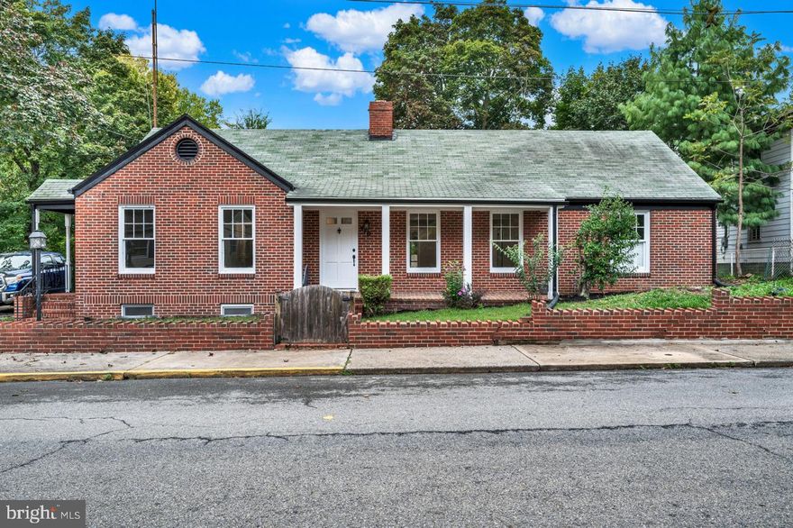 Welcome to 510 Hooge Street, located in historic Martinsburg, WV. This gorgeous all-brick home is absolutely loaded with character and charm. You will find numerous unique details throughout the house, such as built-in cabinets and shelving, exposed brick, custom tile work, exposed beams, and intricate trim, including chair rail, crown molding, and shadow boxes. The kitchen is a true showstopper. It features high-end GE Monogram appliances, a large island with quartz countertops, soft close cabinets, luxury vinyl plank flooring, a gas cooktop, a subway tile backsplash with a mosaic tile inlay, and a decorative fireplace with a beautiful wood mantle. The kitchen leads to a large enclosed sunroom with floor-to-ceiling windows, which expands the living space. Gorgeous dark hardwood floors are on display throughout the main level, matching the home's charm to perfection. The inviting living room features a wood-burning fireplace with built-in bookshelves on either side.  The primary bedroom has an exterior door with direct access to the driveway and a private covered porch. The primary ensuite is simply stunning with its mosaic tile floors, dual vanity, walk-in closet, and an extravagant tiled shower with a rain shower head and glass door. On the opposite end of the home from the primary, you will find two additional bedrooms and a beautifully appointed hall bath. The finished basement would make for a great recreation room or be utilized as an additional bedroom if needed. There is also an unfinished portion of the basement that offers excellent storage space. On the main level, there are stairs that lead to a finished room in the attic that could be used as an office space, kids' playroom, or even an additional bedroom for a large family. The garage has a loft above for even more storage space. The backyard has a courtyard feel to it with its stone patio/walkway and brick fireplace. The shingles on the front portion of the home were replaced around 2017, and the shingles on the rest of the home were replaced in 2024. The indoor and outdoor HVAC units, gutters, and panel box are all new, and approximately 90% of the house has been recently rewired. There is an additional adjoining wooded parcel that also conveys with the sale. This home is an absolute must-see!