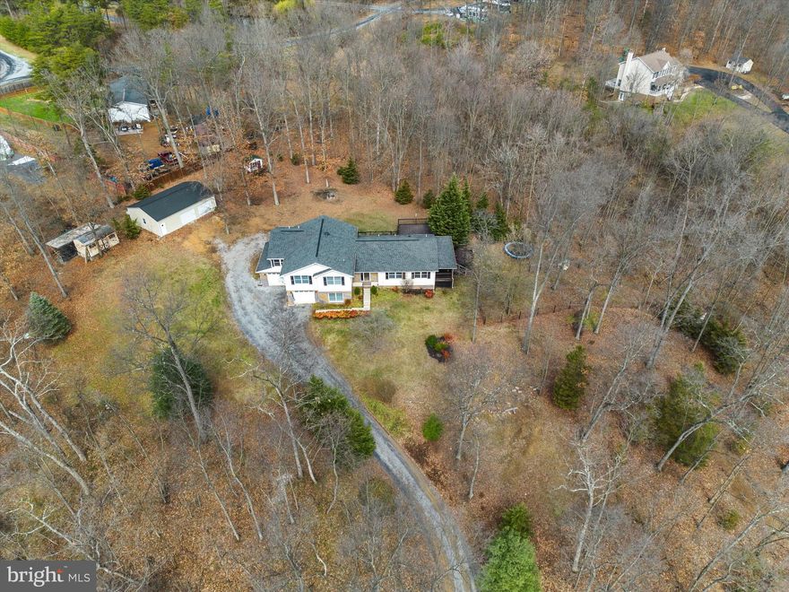 Charming home with exceptional outdoor living and modern upgrades in south Martinsburg! This captivating, single-owner residence on 3 acres is a haven of tranquility, featuring a vast, partially covered wrap-around back deck (reinforced for a hot tub!) that overlooks a flat backyard with picturesque wooded views and a wet weather stream. The property is enhanced by a spacious 24x36 detached building, plus a 2-car attached garage, providing extensive storage and workshop possibilities. The interior is complete with a gourmet kitchen featuring tall cabinets, granite counters, stainless steel appliances, a double oven, and an inviting island. The adjacent dining area has a built-in buffet, and there's also a separate butler's pantry/breakfast area tucked away for the main kitchen. The primary bedroom is an oasis of comfort that includes cork floors, expansive closets, a heated bathroom floor, and a modern tile shower.  Three other rooms on the upper level provide options for additional bedrooms, office space, etc. The lower level offers a spacious rec room, full bath, and additional cozy family room, enhancing the overall living space of this 3,100+ square foot home. Additional highlights include a new roof in 2015 and an energy-saving whole house attic fan. Located just minutes from shopping, dining, and commuter routes, this one could be the forever home you've been waiting to find!