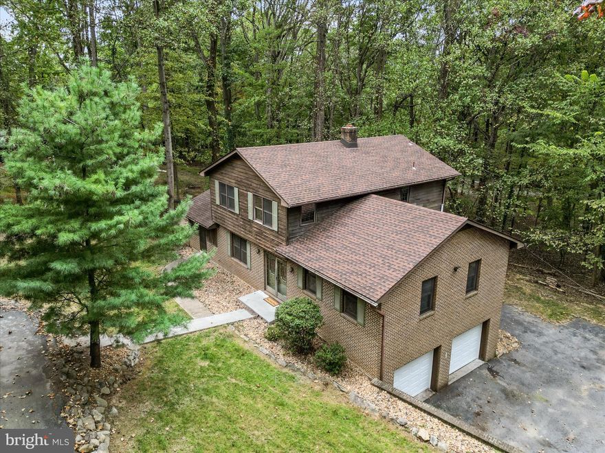 Get a great deal on this roomy 4-bed/3.5-bath brick home nestled on a 2-acre wooded property with no HOA.  Featuring all new LVP flooring throughout, a fresh coat of paint, and brand new garage doors, this residence is move-in ready and available immediately. You'll love the unique floor plan with a huge raised family room that provides ample space to spread out and relax. Plus the spacious screened in porch offers an ideal outdoor area for enjoying the natural backdrop of the beautiful fall colors. The kitchen is equipped with stainless steel appliances, wood cabinetry, and a built-in storage pantry. There's also an attached dining room and living room with half bath on the main level. Upstairs are 3 bedrooms and 2 full baths, including an ensuite bath with a walk-in shower. The lower level not only has access to the attached 2-car garage but also a 4th bedroom and another full bathroom with a jack-n-jill connection to a bonus room. The laundry and backyard access are also available from the basement level. A back deck, wraparound driveway, and another detached garage afford even more amenities. With proximity to the close-by Mountian Lake Club along with commuter routes and town conveniences, this location makes country living easily accessible. Start your next chapter here with an investment in the growing area of Jefferson County, WV!