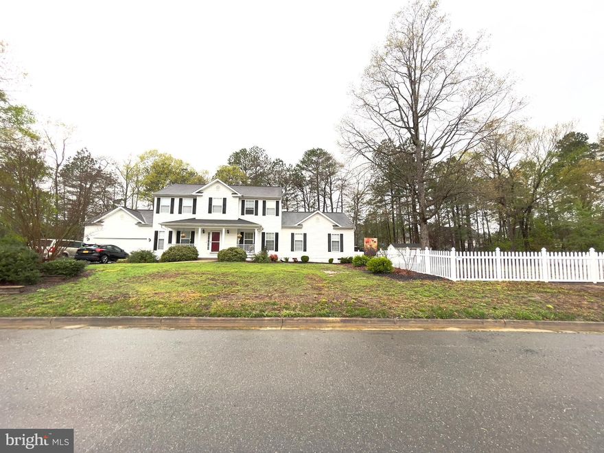Close to everything . . . and the grilling is easy on your spacious deck! This charming 5-bedroom 3.5-bath colonial home is a remarkable find in the Monmouth Village development, within the highly desirable community of Dahlgren.     From its super large fenced yard, located on a quiet, low-traffic street, the home is convenient to the various shopping and dining destinations and the fun of  Barnesfield  Park. The proximity to concentrations of employment (Naval Surface Warfare Center Dahlgren & Mary Washington College Dahlgren campus) makes for a super easy commute.
Fenced in the rear and huge side yard offers seclusion and plenty of space for leisure.  This side yard has SO much potential.  Perhaps a pool, playground or garden area?   Let your dreams be your guide!   Representing the welcoming personality of the home, a front-facing, breezy porch is a structural greeting to passers-by and a nice spot for relaxing with refreshments, whether morning coffee or afternoon tea.   The huge 12 X 32 rear deck is the perfect platform for the household barbecue and some fun outdoor meals.   The rear yard also includes a concrete patio, ready for your games or extended entertaining space.  
Inside, the home features a wealth of comforts. The centerpiece of the living room is a gas fireplace that inspires gathering and conversation.
Flowing like easy conversation into the dining room, living room, and deck, the kitchen is large enough to accommodate a food prep assistant or two.  Enjoy dining and conversations around the large center island.   
The luxuriously oversized en suite primary bedroom, conveniently located on the main-floor, is well-designed and tranquil. In addition to the convenience of the private bathroom, you will find ample closet space to let your wardrobe breathe. A sitting area works as yet another functional component.   This en suite bathroom is handicap ready with roll in shower and corner seating.  There is also a wonderful Jacuzzi tub here as well.    The other 4 bedrooms - unique, quiet, and with plenty of closet space-- are located above the ground floor for enhanced privacy.   One of the 4 here is another large primary with bathroom en suite.   A hall bath serve the other 3.   
A double-wide driveway makes ample room for visitor parking, and is connected to an attached two-car garage that is available for its original purpose or for use as additional flex space.   
This lovely home is handicap enabled with a side ramp and also a chair lift from the garage.   
Cross the threshold into a pleasant new life here in King George