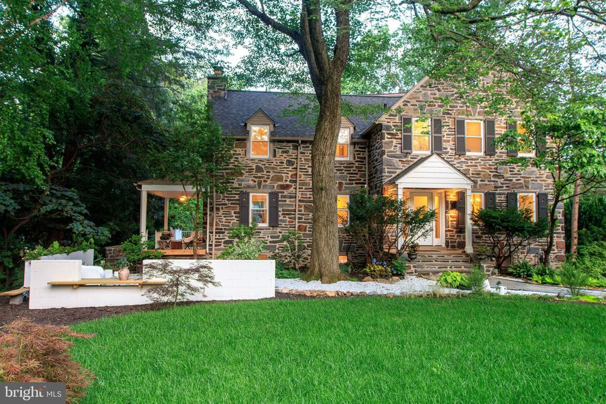 FULL INTERIOR RENOVATION • NEW OPEN-CONCEPT LAYOUT • HIGH-EFFICIENCY WINDOWS & DOORS • TWO FIREPLACES • BUILT-IN BENCHES • FINISHED LOWER LEVEL • MULTI-LEVEL TERRACED GARDENS • FULLY RESODDED LAWN • FLEXIBLE OPEN WORKSHOP / GARAGE  • SERENE FOREST RETREAT SETTING
Nestled within the serene woodlands of Lower Merion, this reimagined 1930s stone residence seamlessly blends historic charm with contemporary sophistication. Spanning 3,838 square feet on a lush 0.45-acre lot, the home offers five bedrooms, two and a half baths, and a harmonious flow of indoor and outdoor living spaces. The polished entry welcomes you with gorgeous hardwood floors that extend throughout the home. The bright and airy formal living room features a wood-burning fireplace and access to the expansive wraparound patio, perfect for entertaining or quiet reflection. The open-concept chef’s kitchen and formal dining area are equipped with stainless steel appliances, white cabinetry, a breakfast bar, custom built-in benches, and a cozy fireplace. From here, head to the backyard, enhancing the connection to nature. A dedicated office space and a conveniently located half bath complete the main level. Upstairs, the spacious primary suite offers ample closet space and a luxurious bath with a unique shower and built-in soaking tub. Three generously sized bedrooms and an updated hall bath with a tub provide comfort and privacy. The third floor features a versatile fifth bedroom and additional storage space. The finished lower level offers a family room and a separate laundry area, adding to the home's functionality. Outside, the property is surrounded by mature trees and terraced gardens, providing a rare combination of privacy and openness. Layered patios and a forest living room beyond offer an outdoor extension of life beneath the trees. The garage has been transformed into a flexible open workshop—perfect for creative use, gardening, or storage—while remaining easily convertible for vehicle use. Discover the charm of this ideally located residence in the award-winning Lower Merion School District. Situated just a short stroll from the heart of downtown Narberth, this home offers unparalleled access to local parks, boutique shops, diverse dining options, a historic movie theater, and vibrant community events. Whether you're enjoying a peaceful walk to places of worship or participating in neighborhood festivities, everything you need is within easy reach. This residence is a testament to thoughtful design, where tradition meets modern clarity in a tranquil woodland setting. It is, in essence, a forest retreat—where life flows gently between stone, sun, and trees.